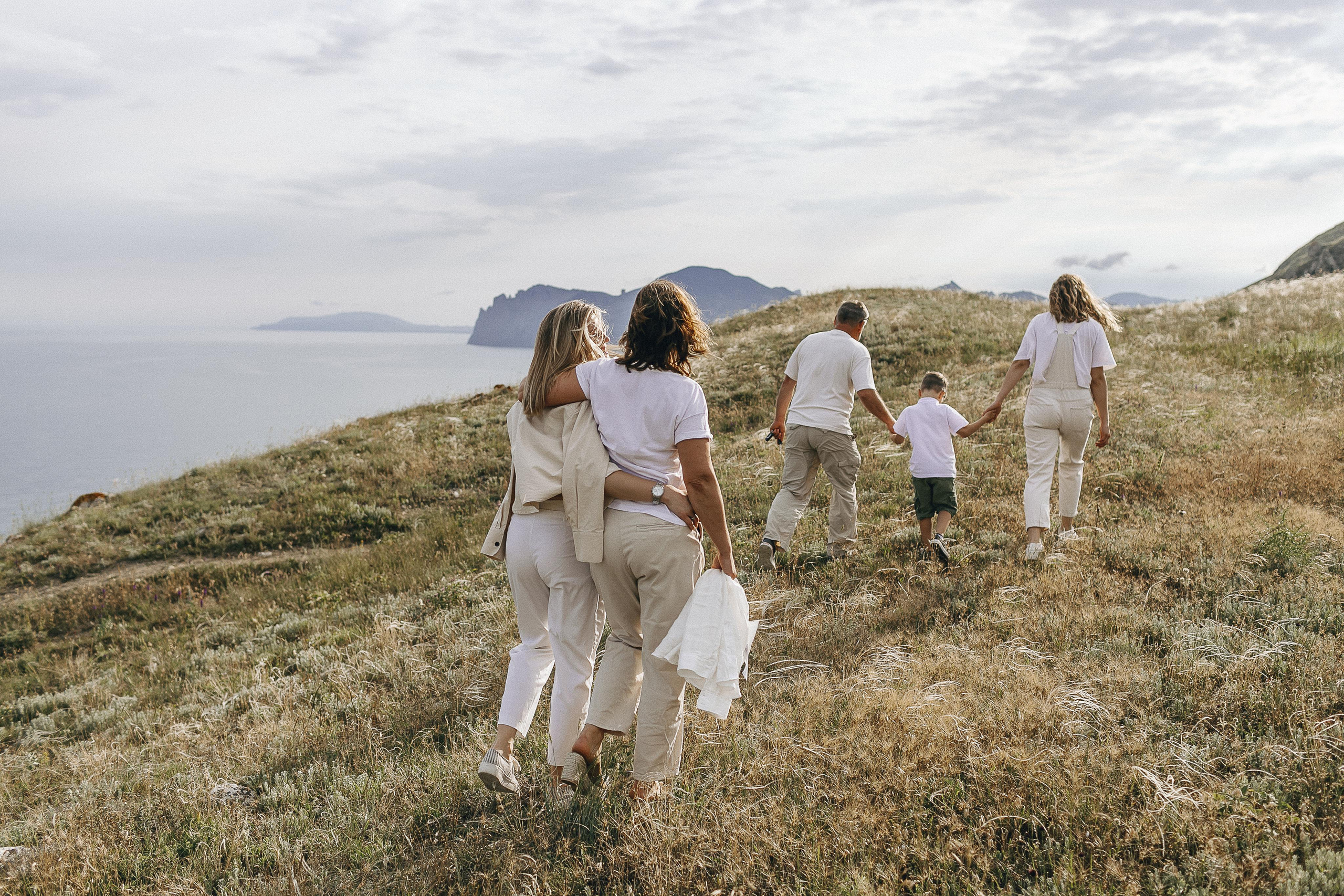 Семья из пяти человек идет по холмам Коктебеля, а лучи солнца ведут их. Бронь отдыха в Севастополе.