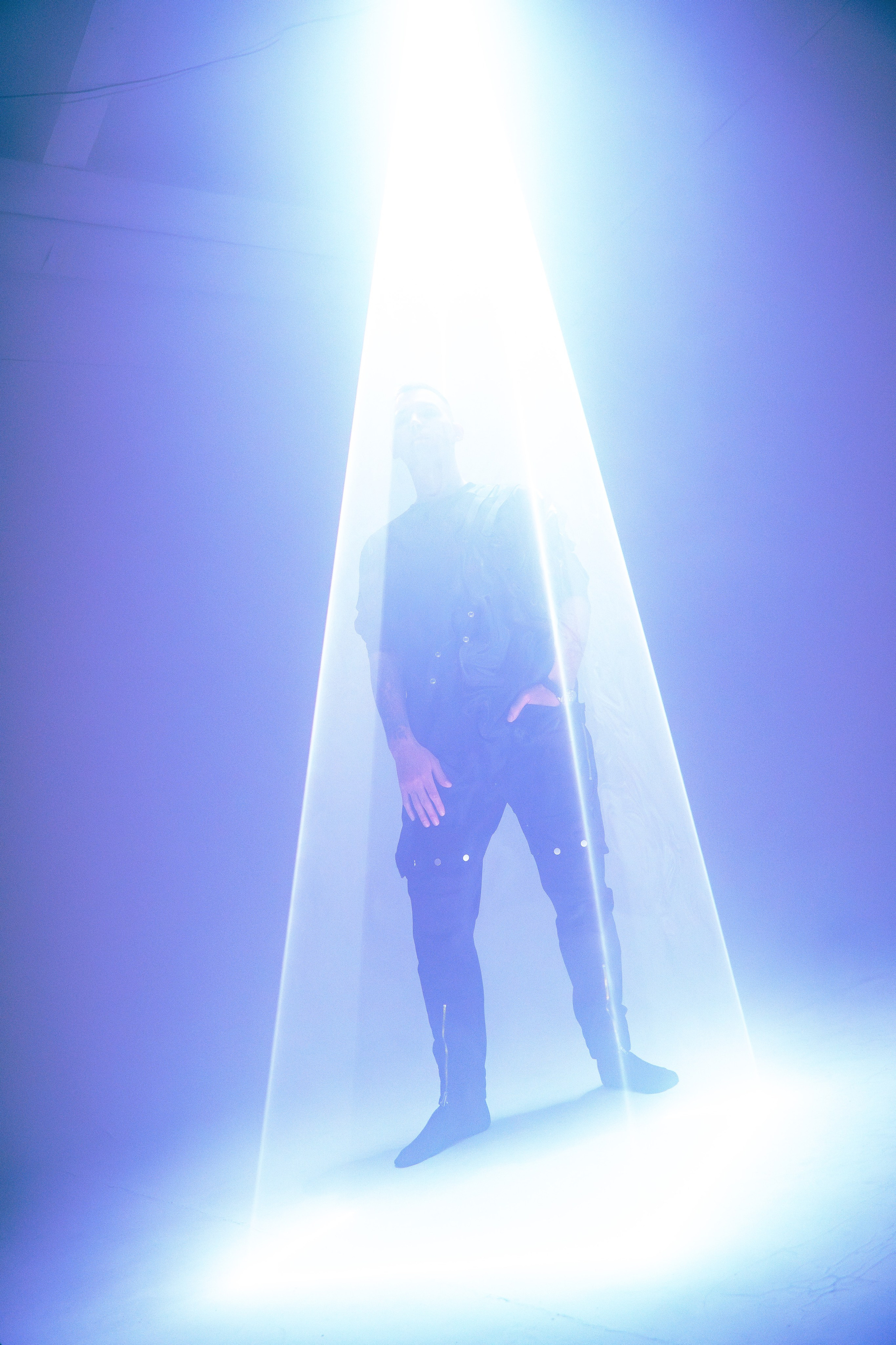 Низкая перспектива: человек в лучах белых и синих лазеров