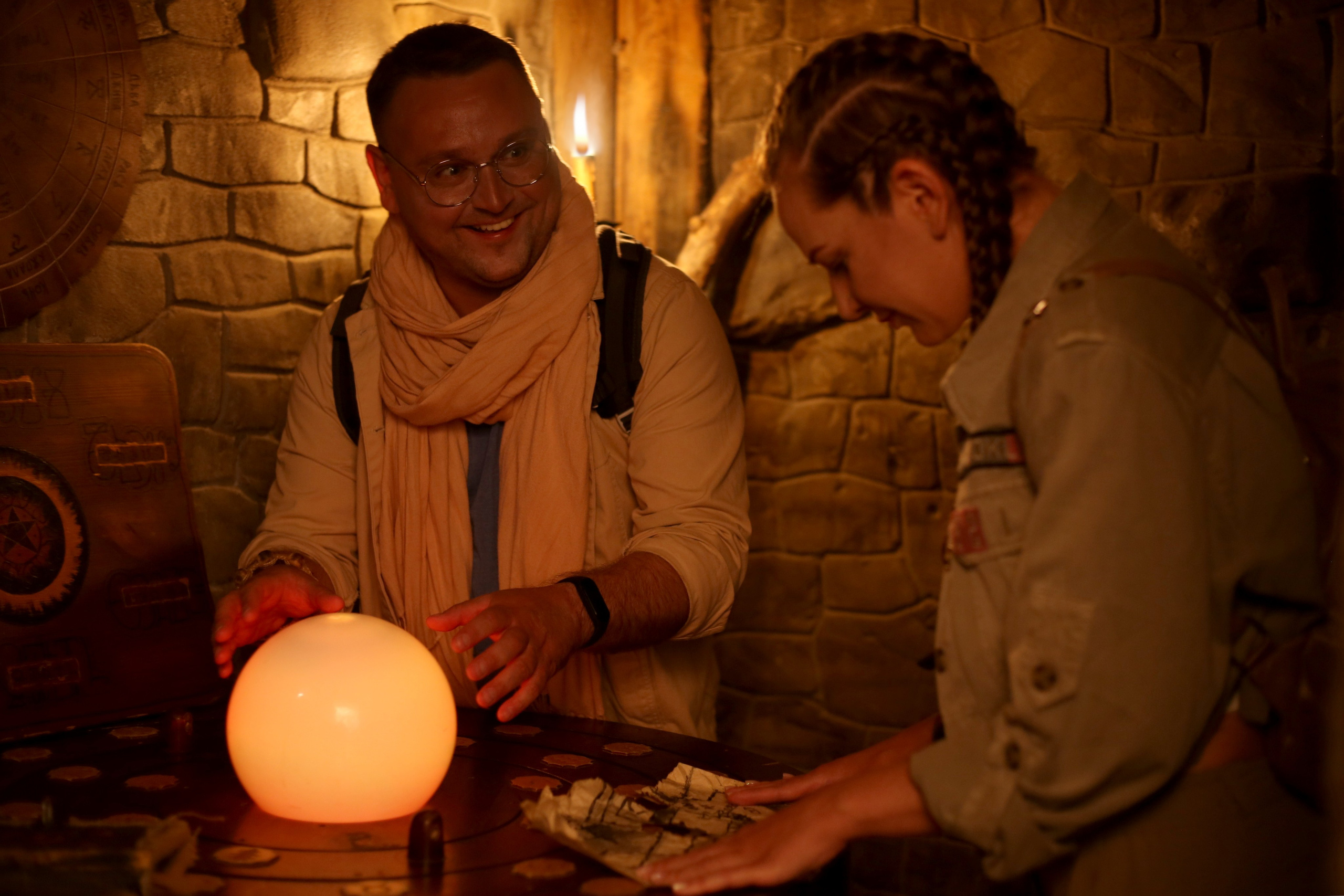 Парная фотосессия «Как в кино»: пара за столом со светящимся шаром и картой