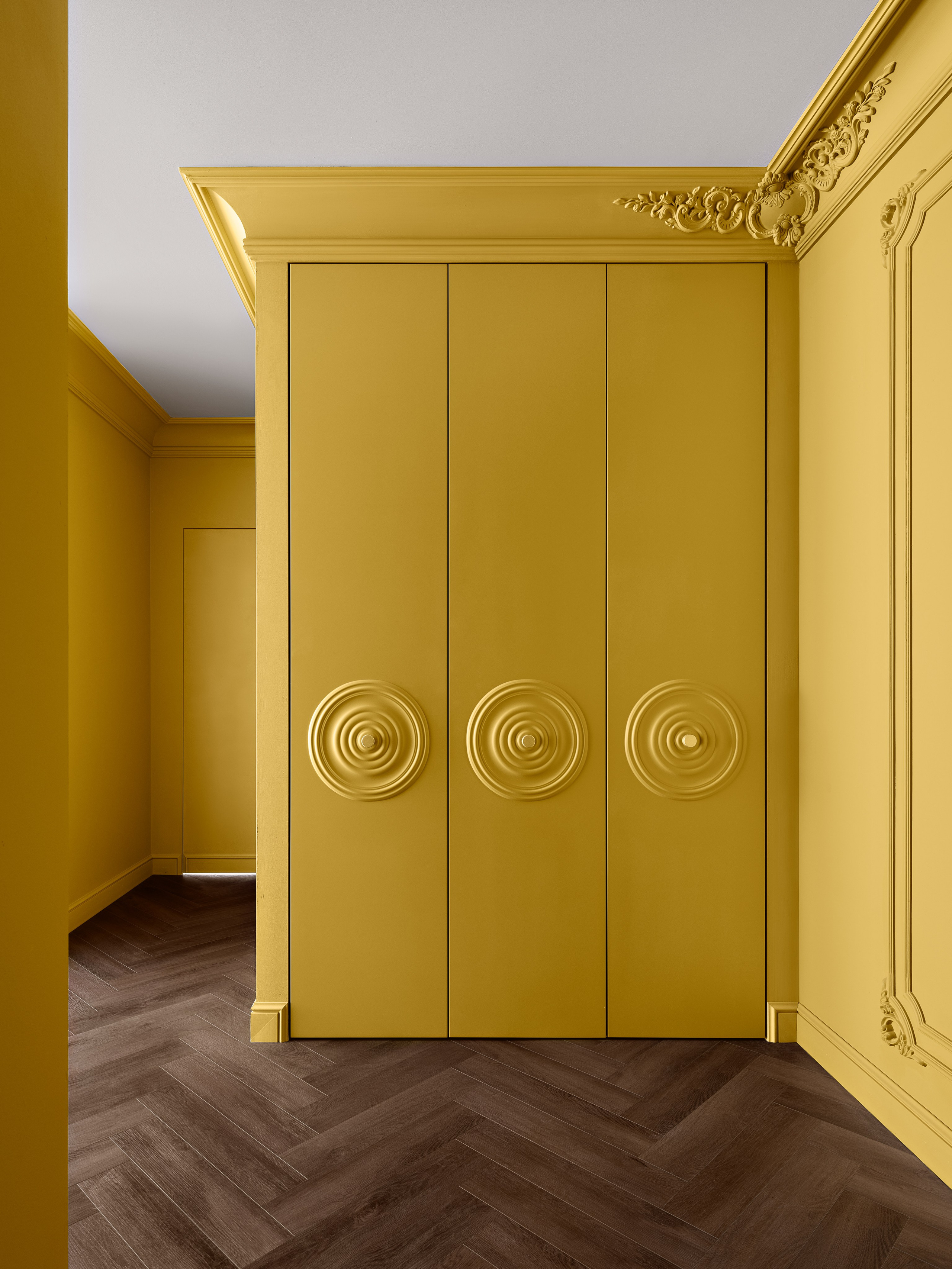 Стильная прихожая с яркими жёлтыми стенами, декоративной лепниной и встроенным шкафом с рельефными фасадами, подчёркивающими современный дизайн интерьера; работа дизайнера Антона Логинова, стилист Алёна Мощенская, фото Сергея Денисенко.