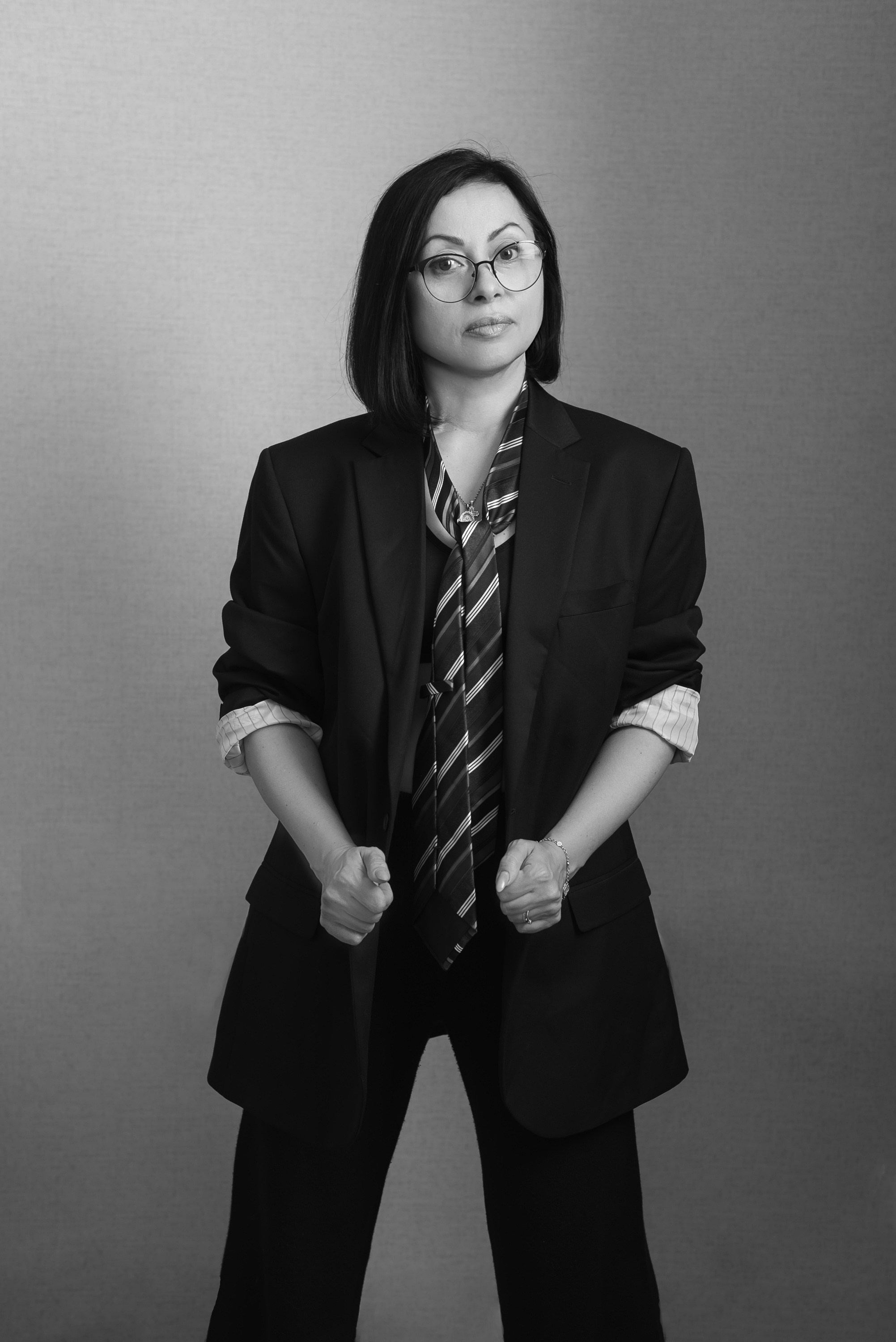 Девушка стоит в черном костюме с галтуком.