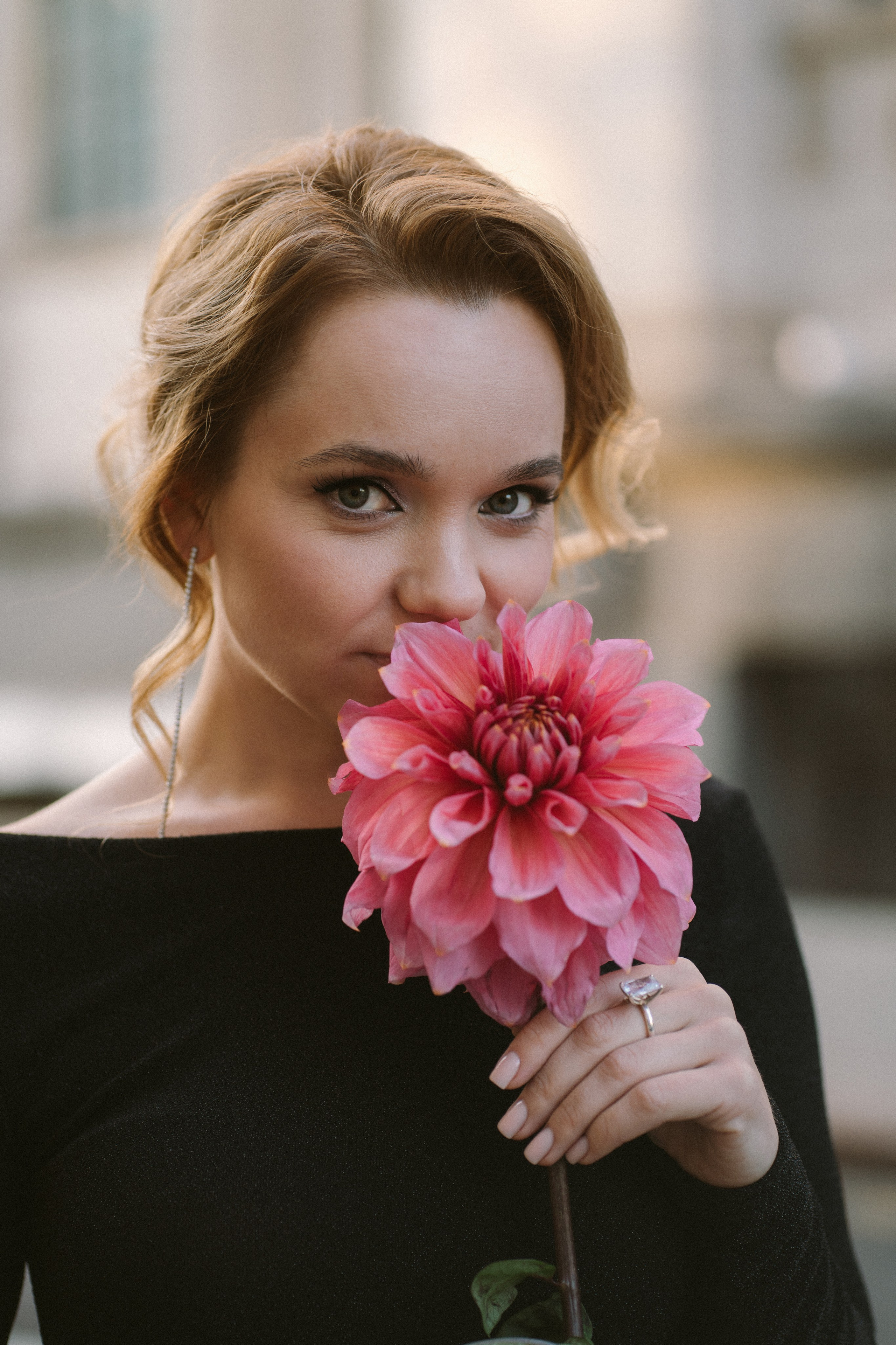 девушка с рыжими волосами нюхает большой розовый цветок