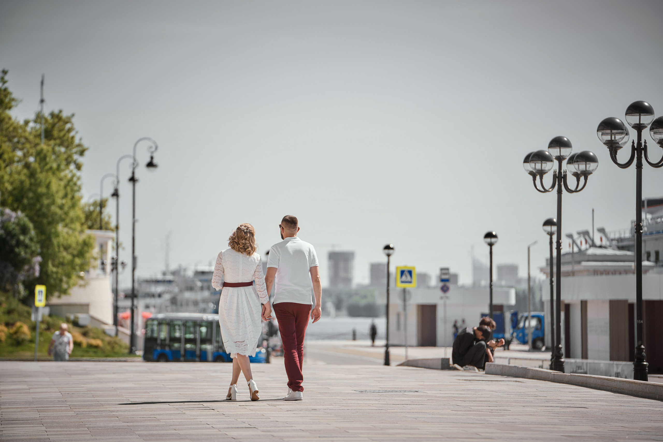 девушка в белом платье гуляет по набережной Москвы реки и речного вокзала с парнем в красных штанах и белой рубашке