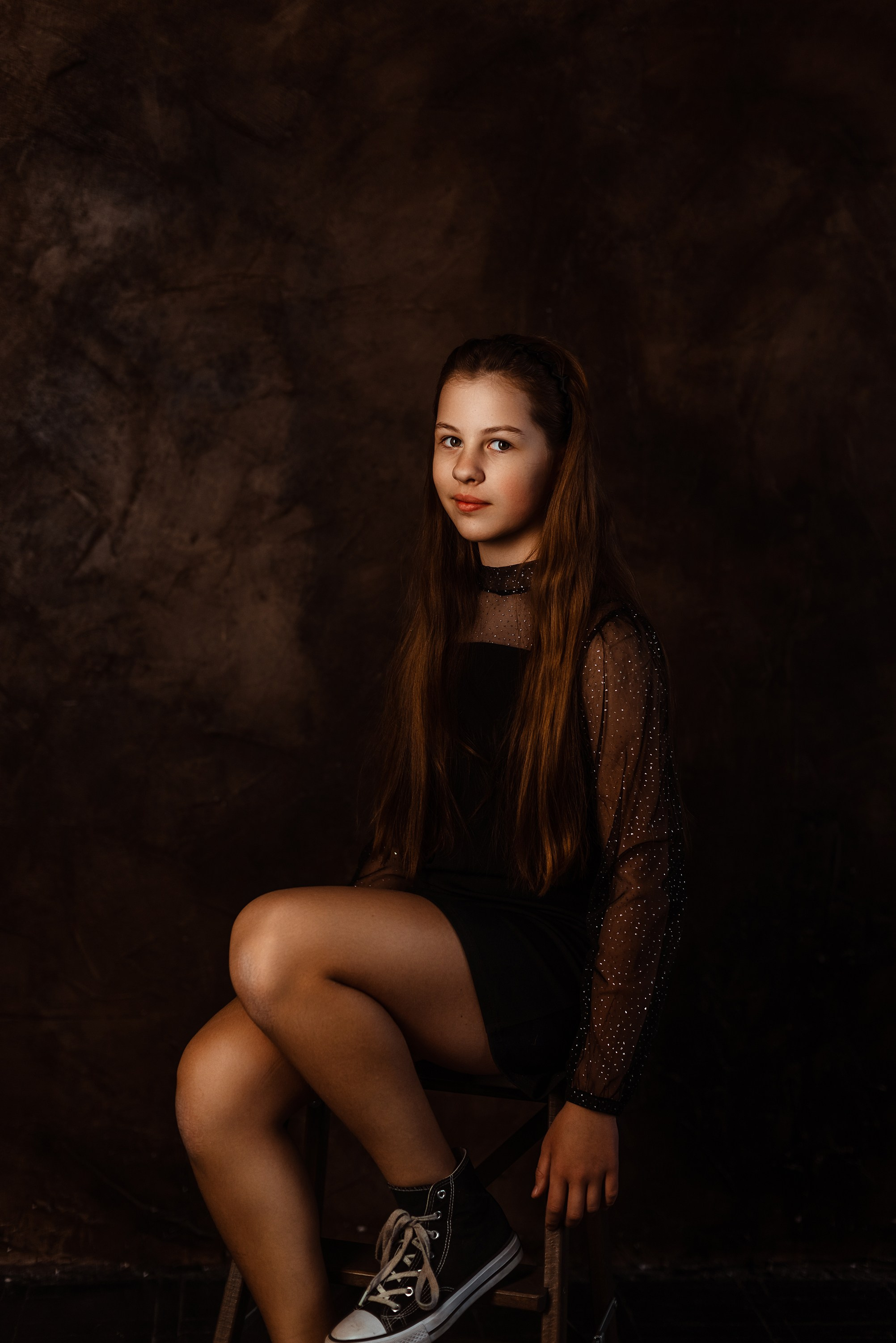 Весёлый снимок старшей сестры, гордо демонстрирующей свою красивую причёску и платье, в праздничной атмосфере фотостудии