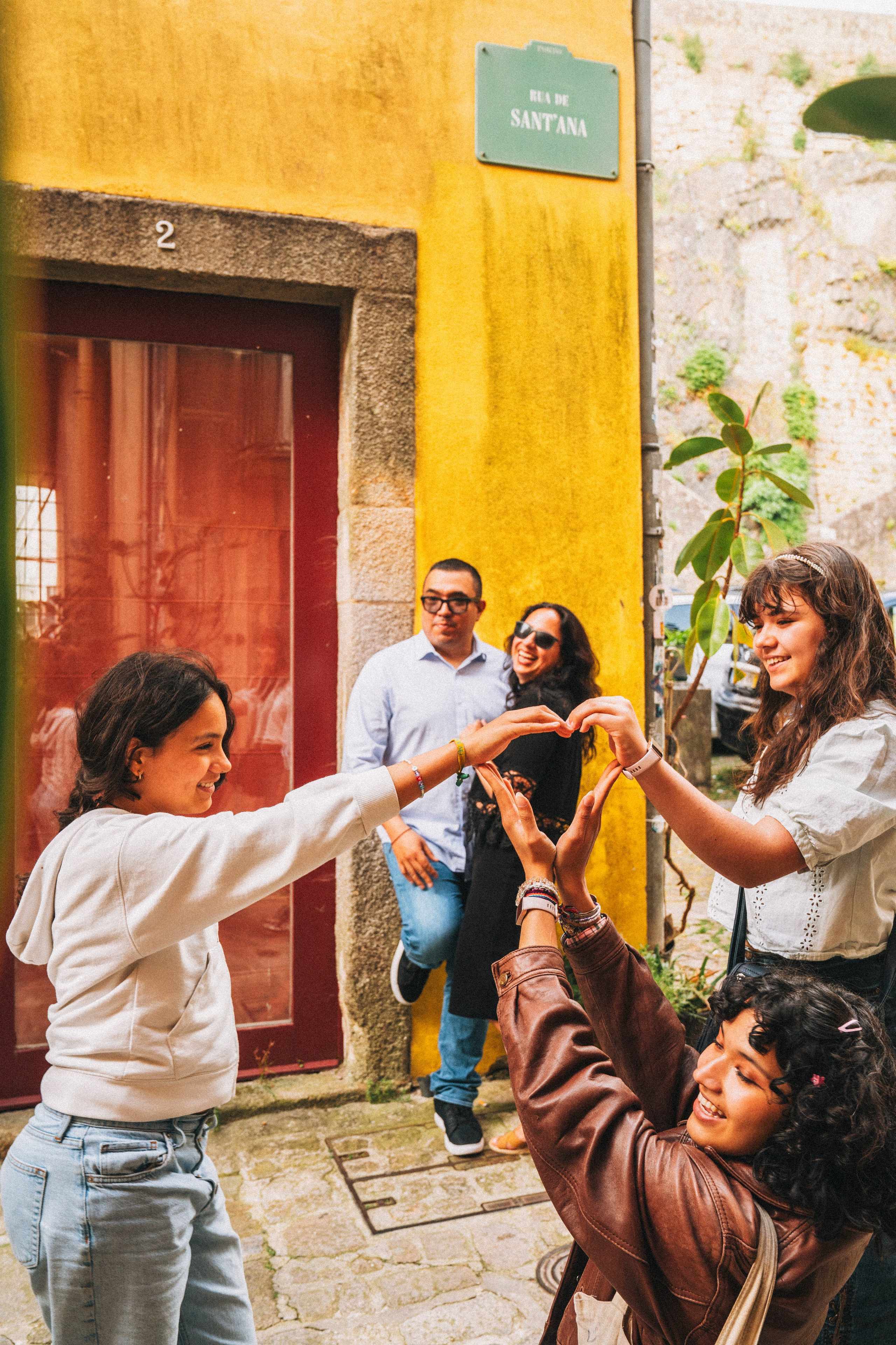 Группа людей семья влюбленные гуляет по живописной узкой улочке в Португалии, окружённой старыми домами и зеленью.