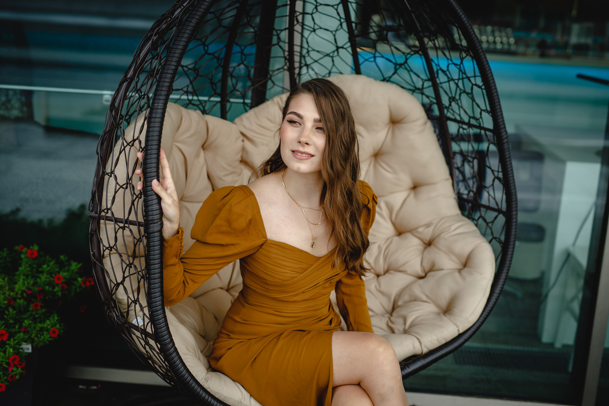 Девушка с длинными волосами в коричневом коктейльном платье на качелях коконе