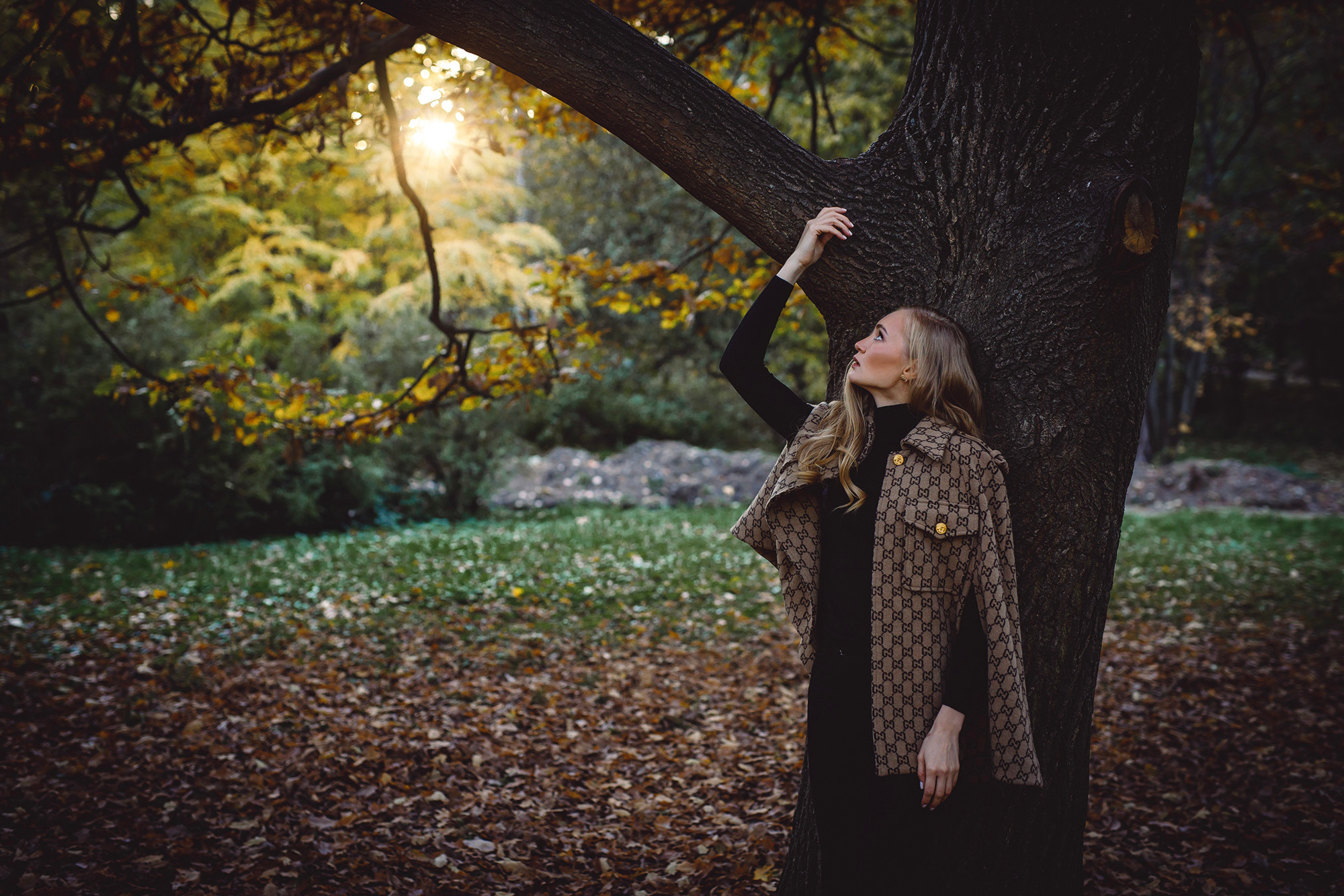 Девушка блондинка с длинными волосами в осеннем лесу на закате в кейпе Гуччи и черной водолазке