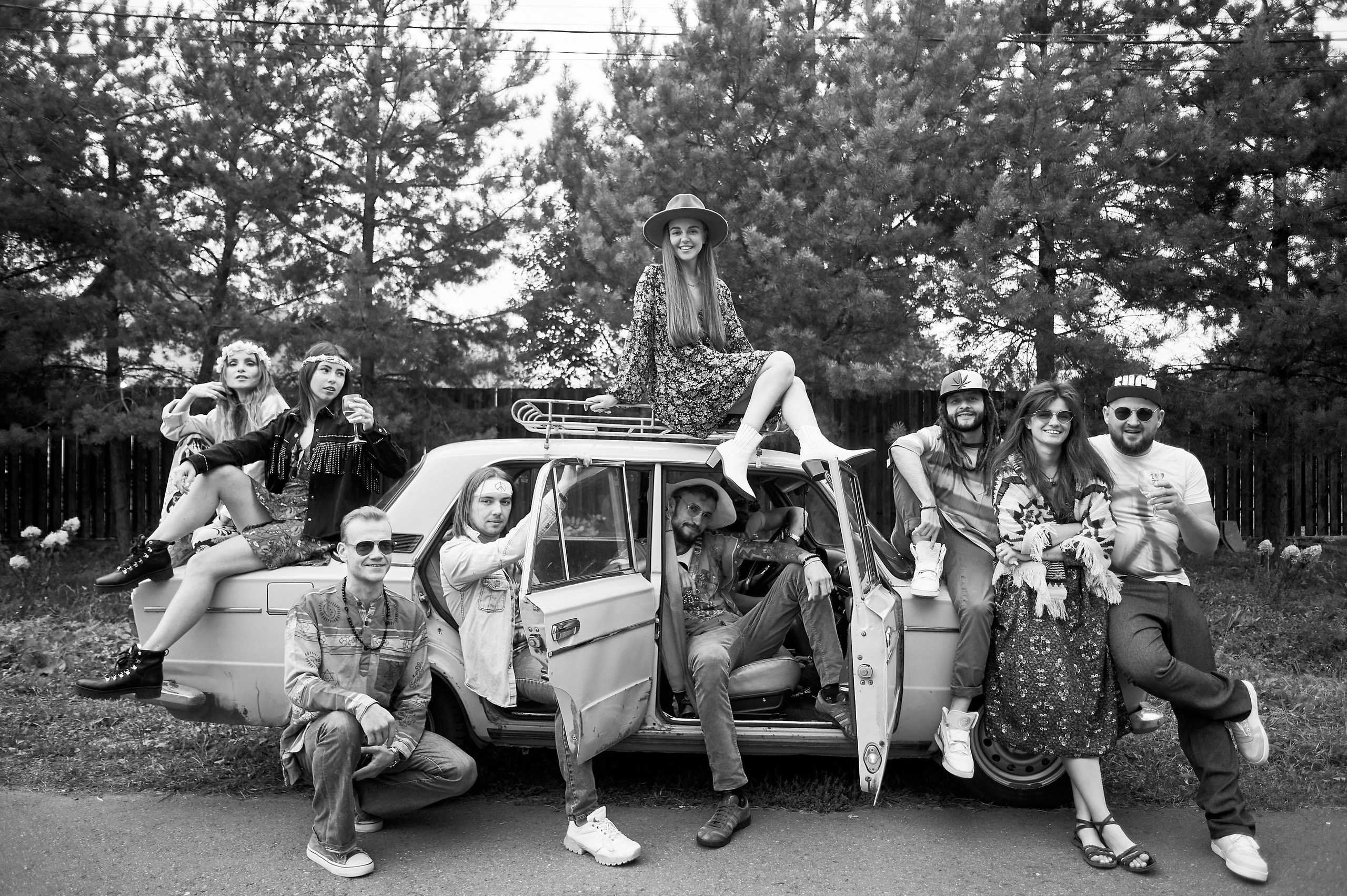 Много людей улыбаются и сидят на старой машине