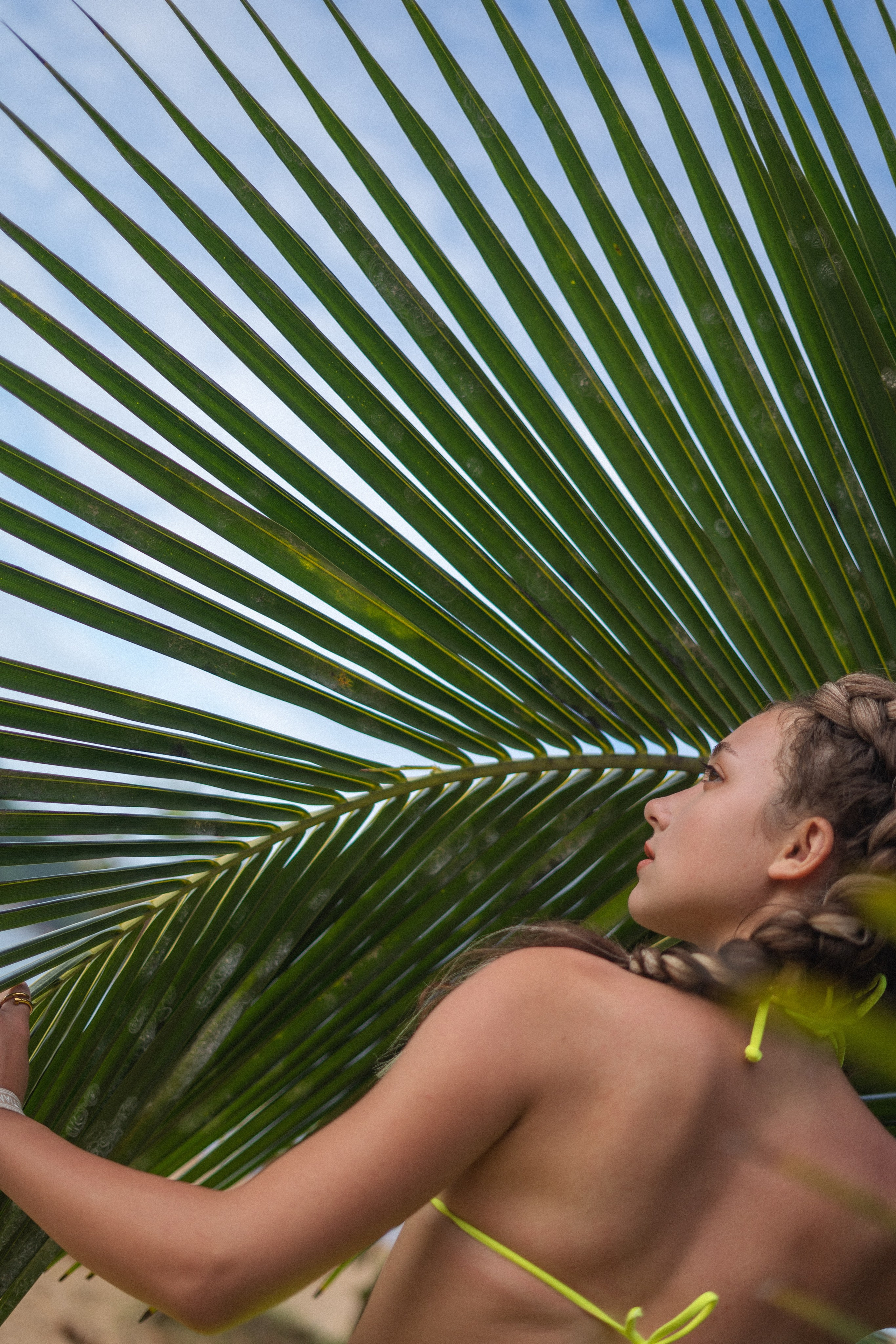 a girl with braids in a yellow swimsuit at sunset by the ocean