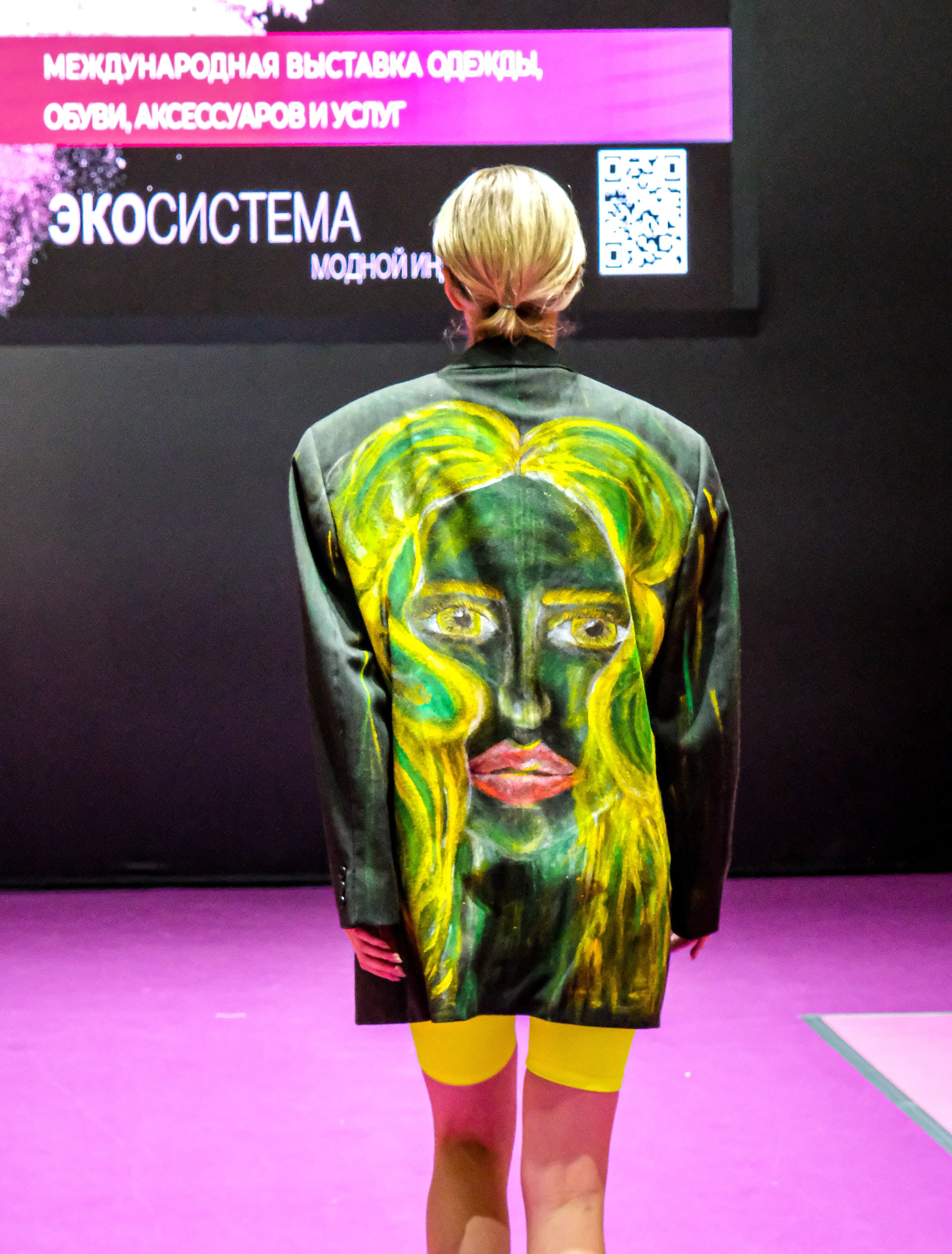  "Модели в ярких нарядах проходят по подиуму во время показа мод, освещенные яркими софитами и окруженные восторженными зрителями."