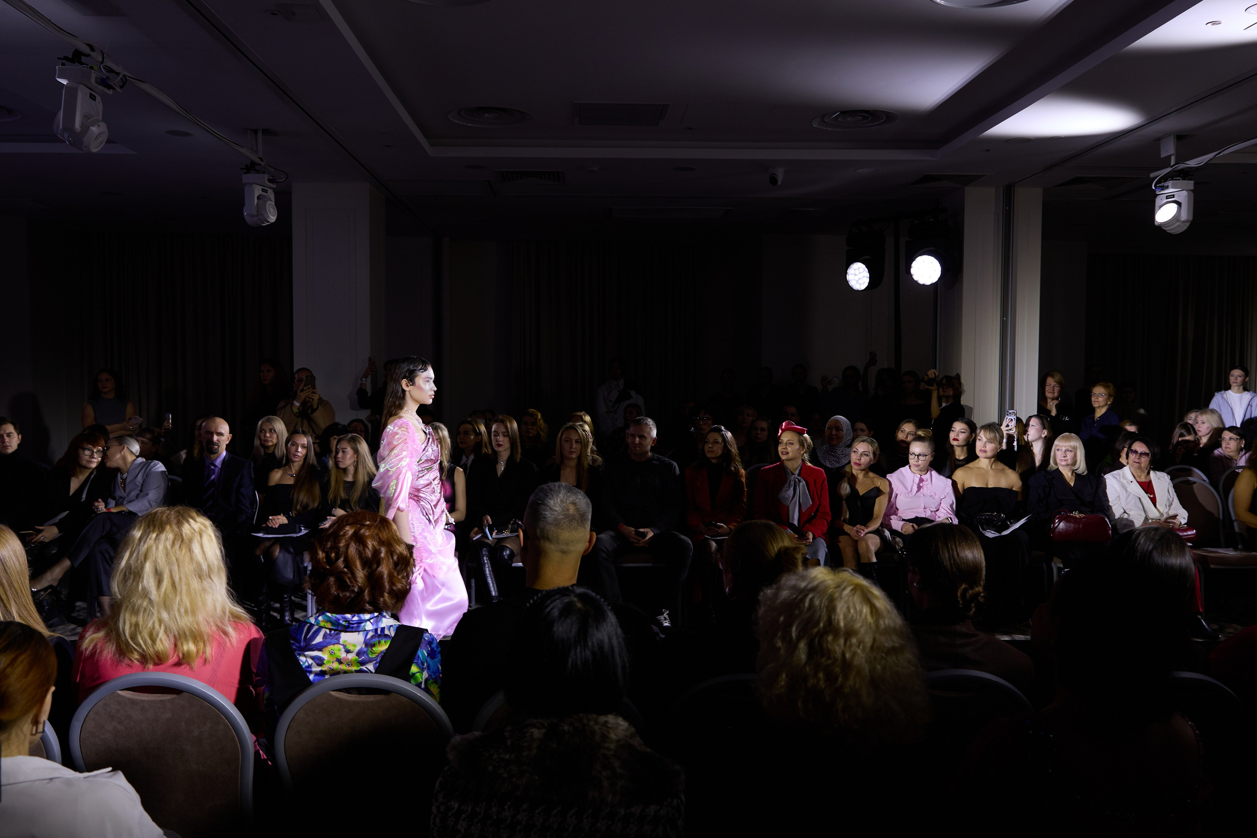 Фотография, снятая из-за кулис: вид на освещенный подиум и зрительный зал, погруженный во тьму. Символизирует разделение сцены и зала, артиста и зрителя.