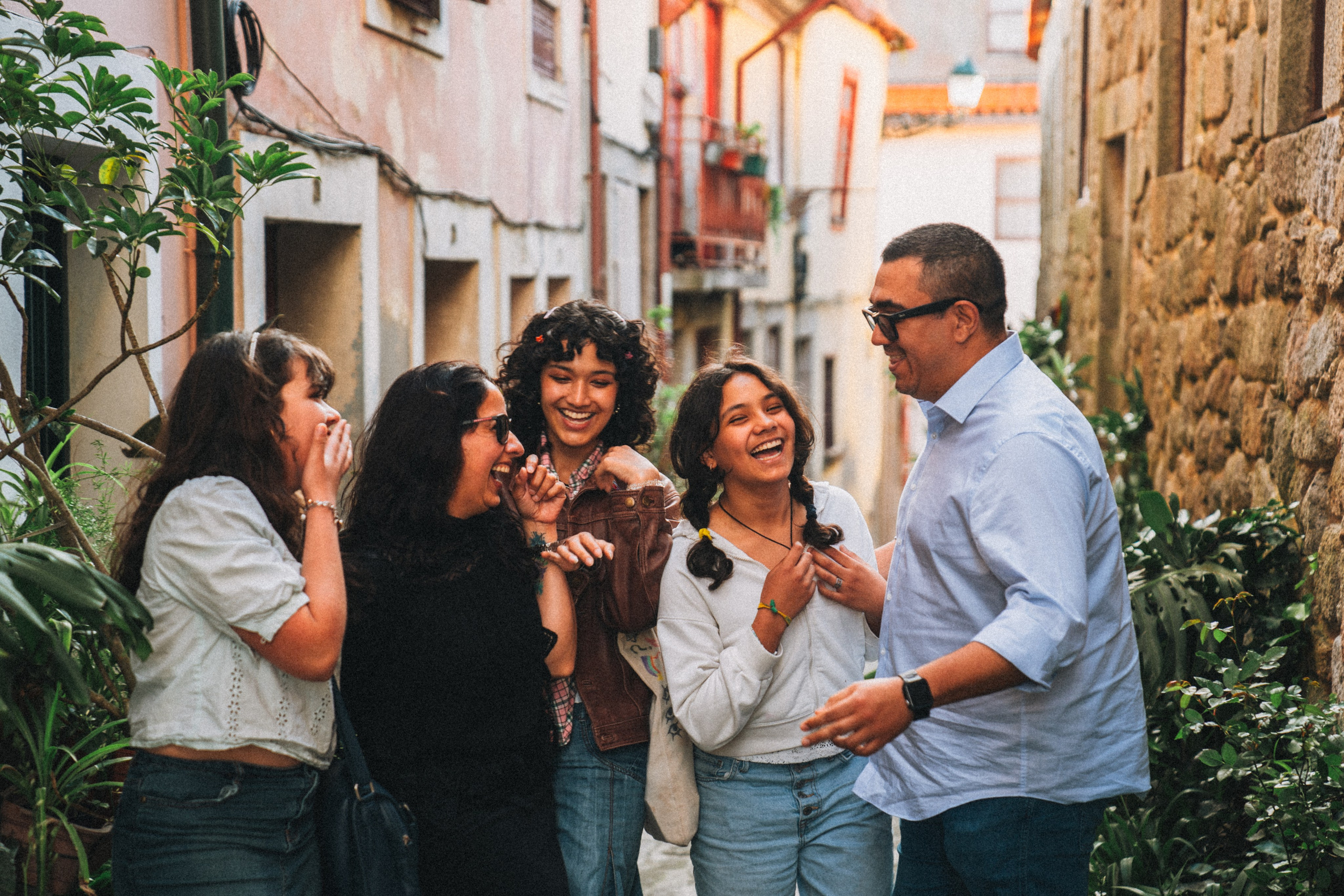 Группа людей гуляет по живописной узкой улочке в Португалии, окружённой старыми домами и зеленью.
