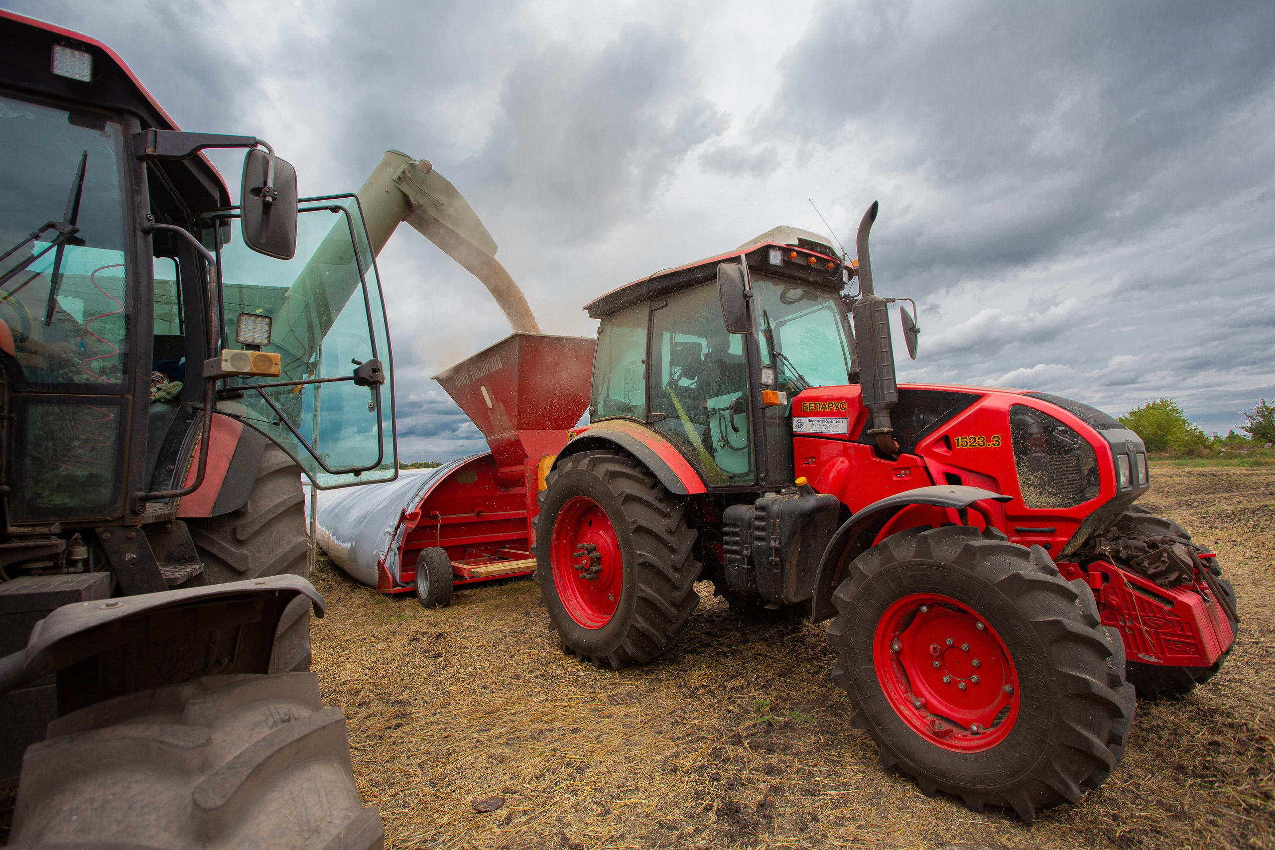 Сельскохозяйственная техника на уборке урожая и загрузке зерна в рукава для хранения 