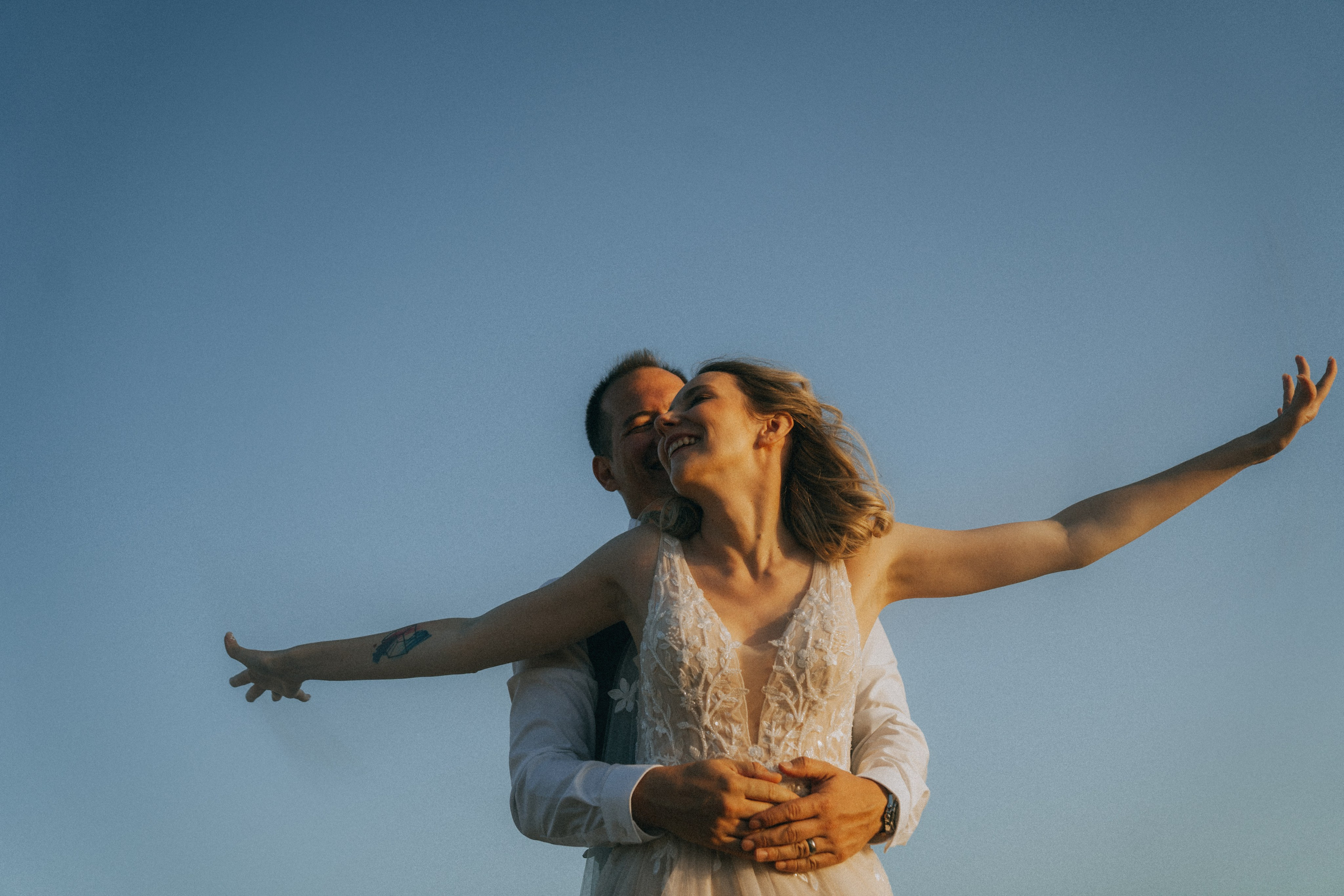 Счастливая пара жених и невеста целуется на фоне волн  скал и заката у океана.