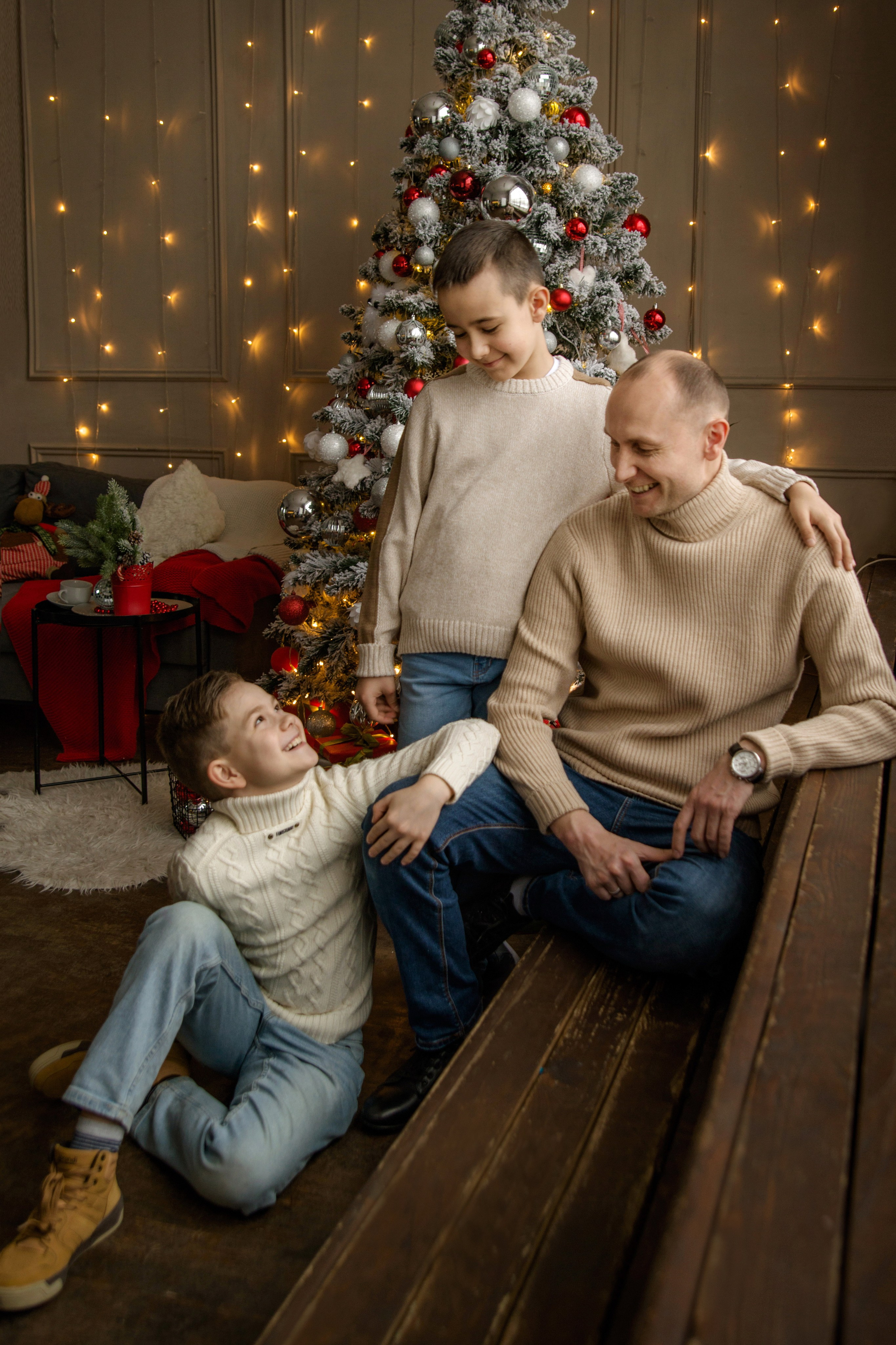 Семейная фотосессия отца и двух сыновей на фоне новогодней елки