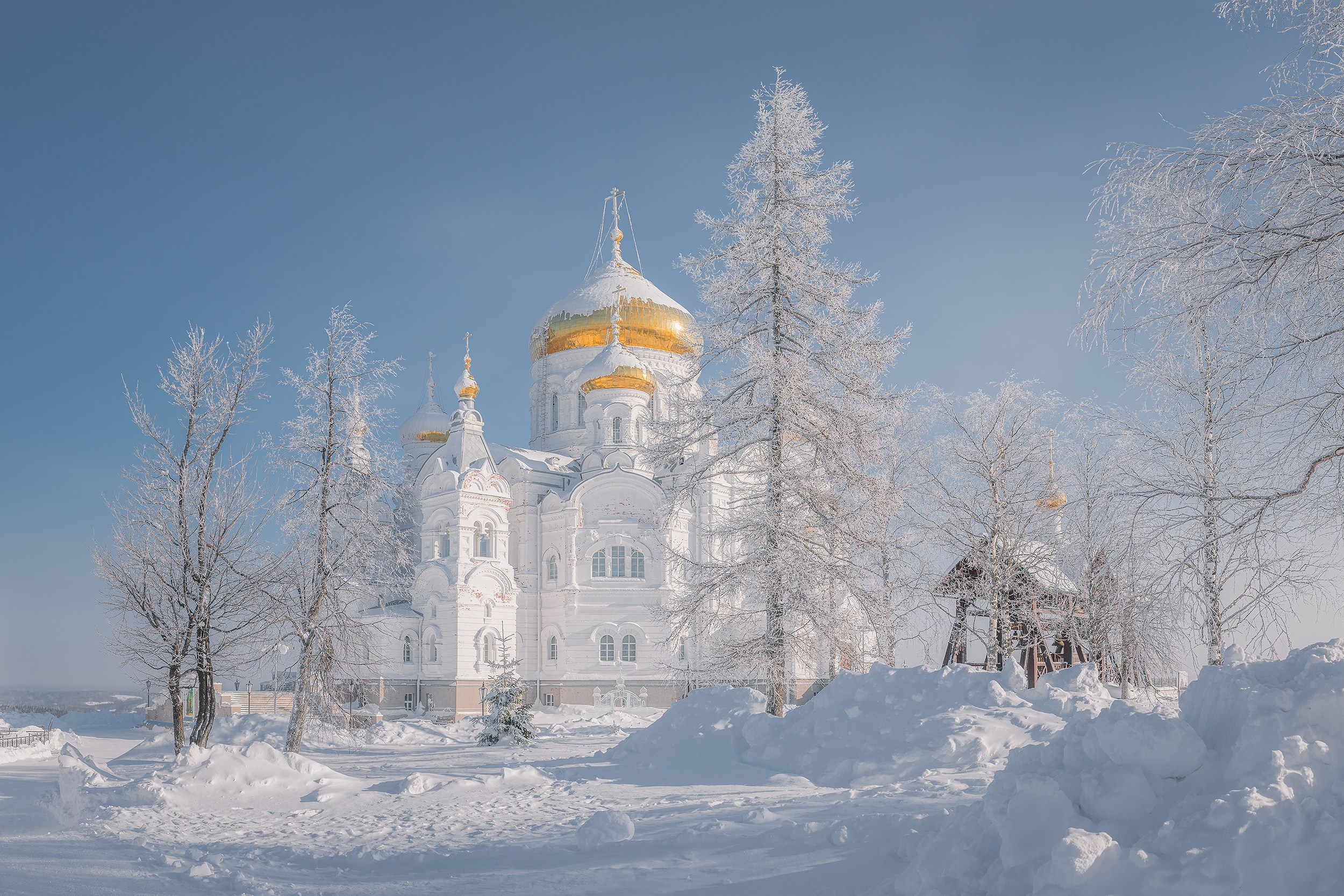 Белогорский монастырь на фоне заснеженных деревьев и голубого неба