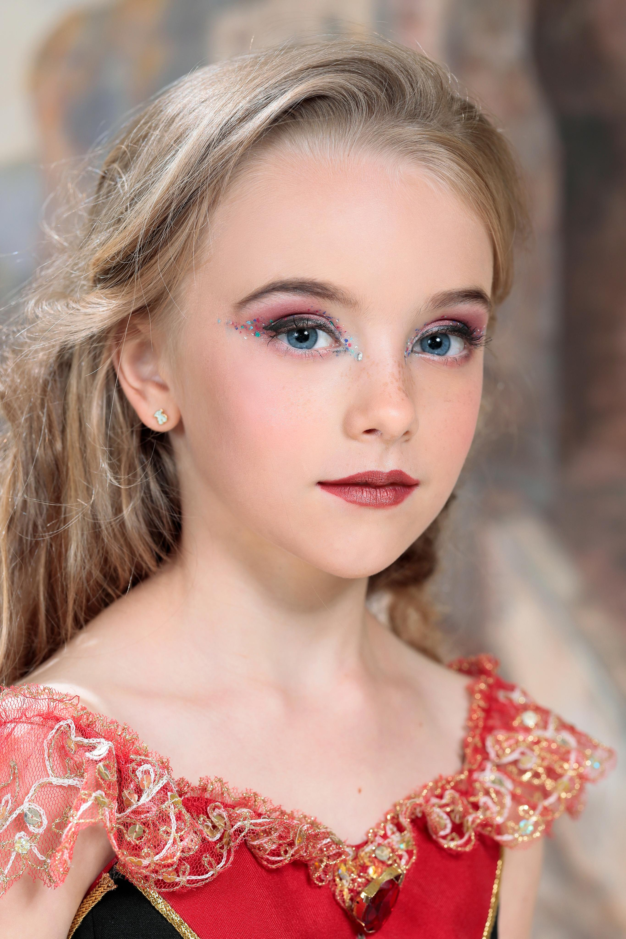 Портрет девочки со светлыми волосами и голубыми глазами в красном платье.