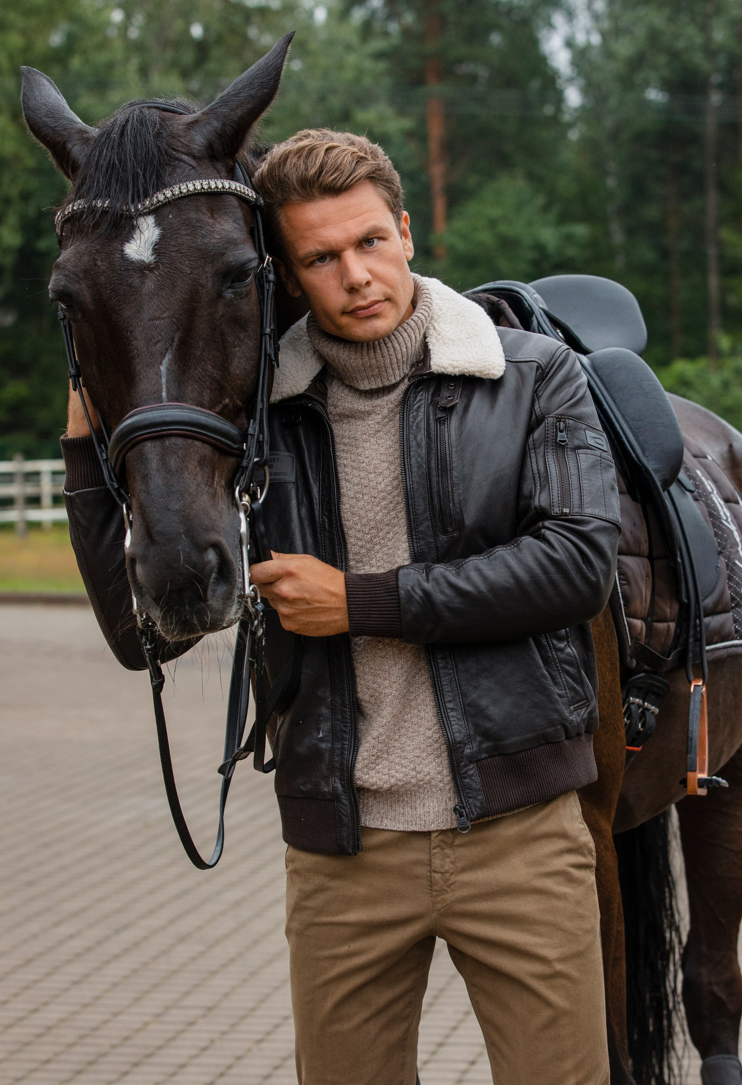 Мужчина модель в кожаной куртке стоит с лошадью