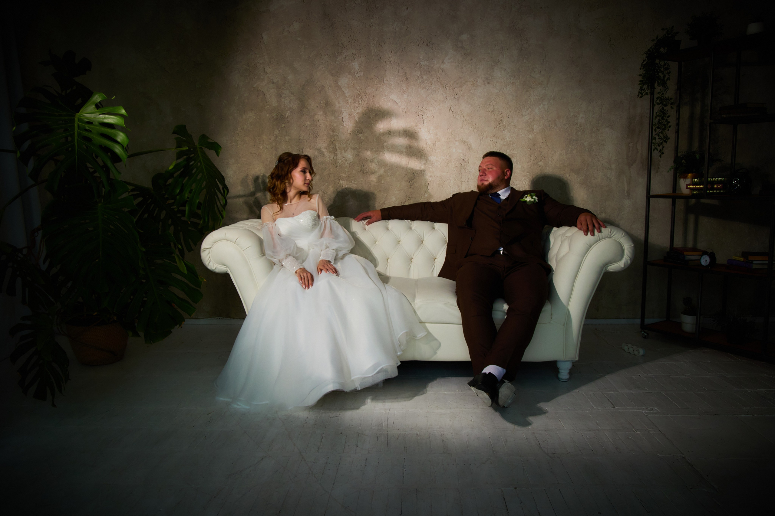 жених и невеста сидят на белом красивом диване