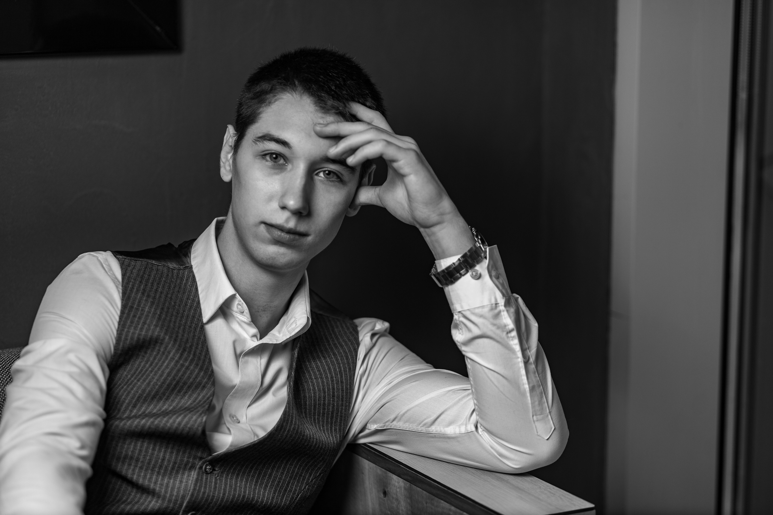 Молодой человек облокотился на кисть левой руки