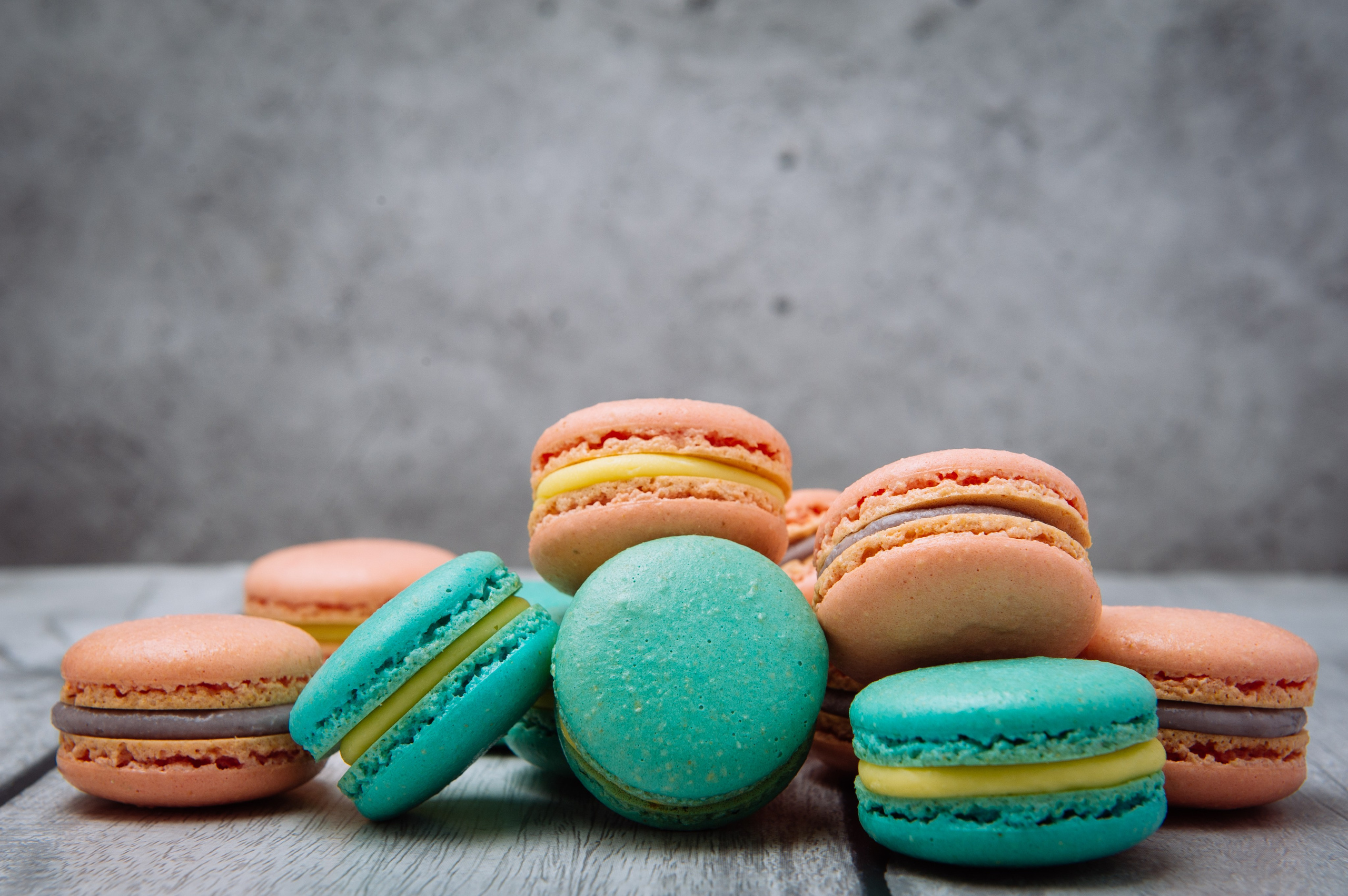 Яркие пирожные макарон на столе, разноцветные и аппетитные. Крупный план пирожных макарон, текстура и детали начинки.