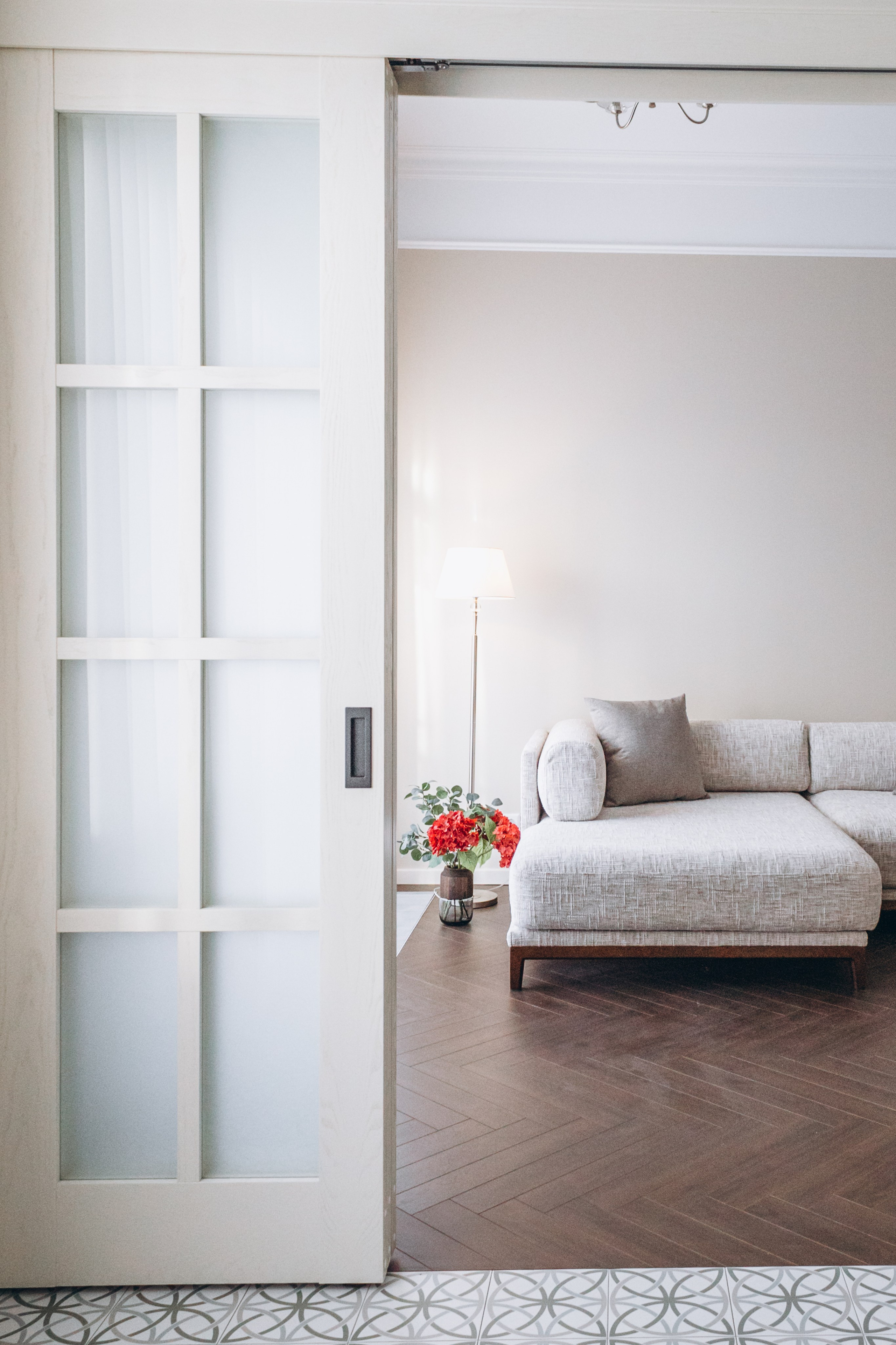 Современная гостиная с серым угловым диваном и раздвижными дверями на кухню