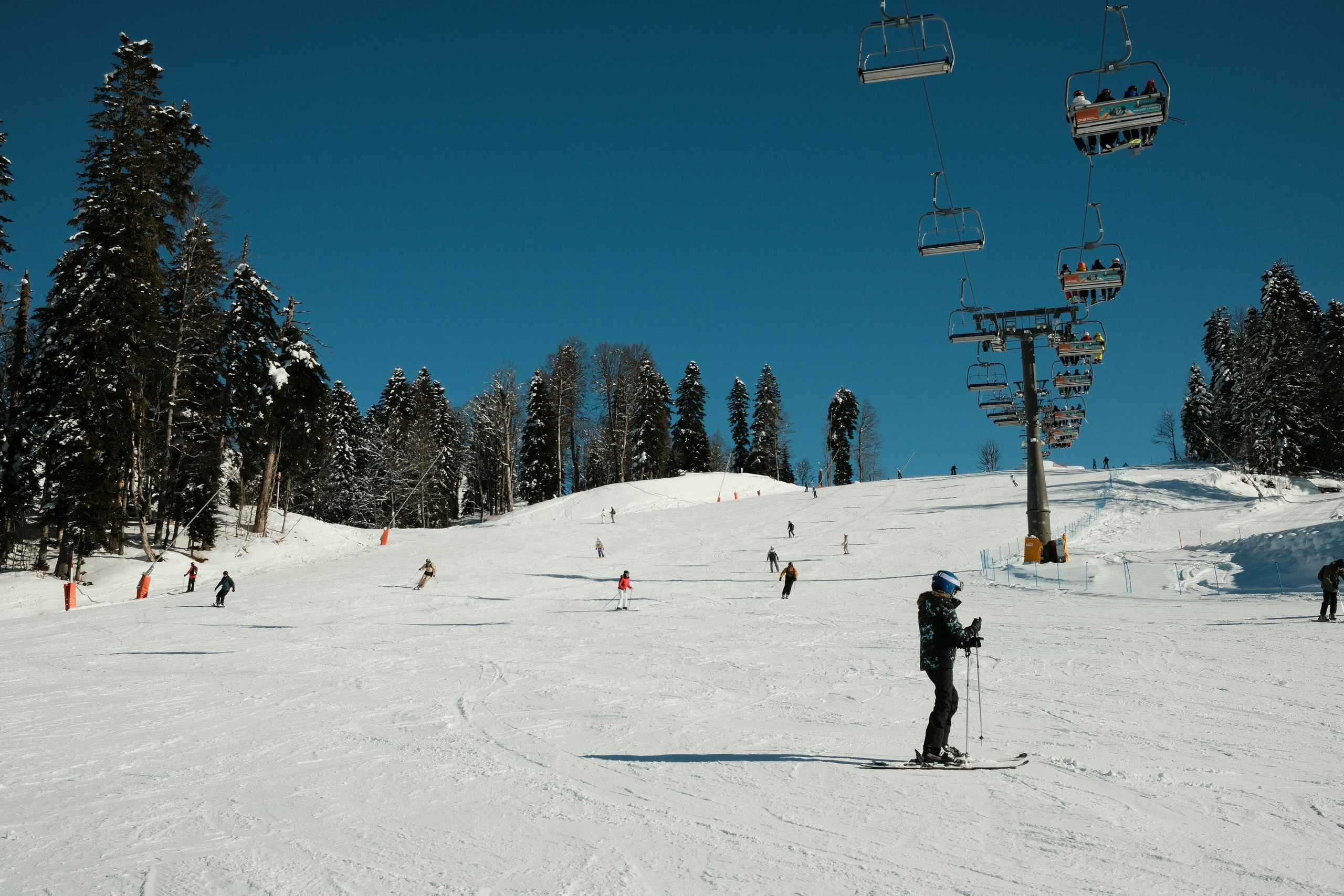 Горнолыжники едут по склону Лауры на фоне подъёмника
