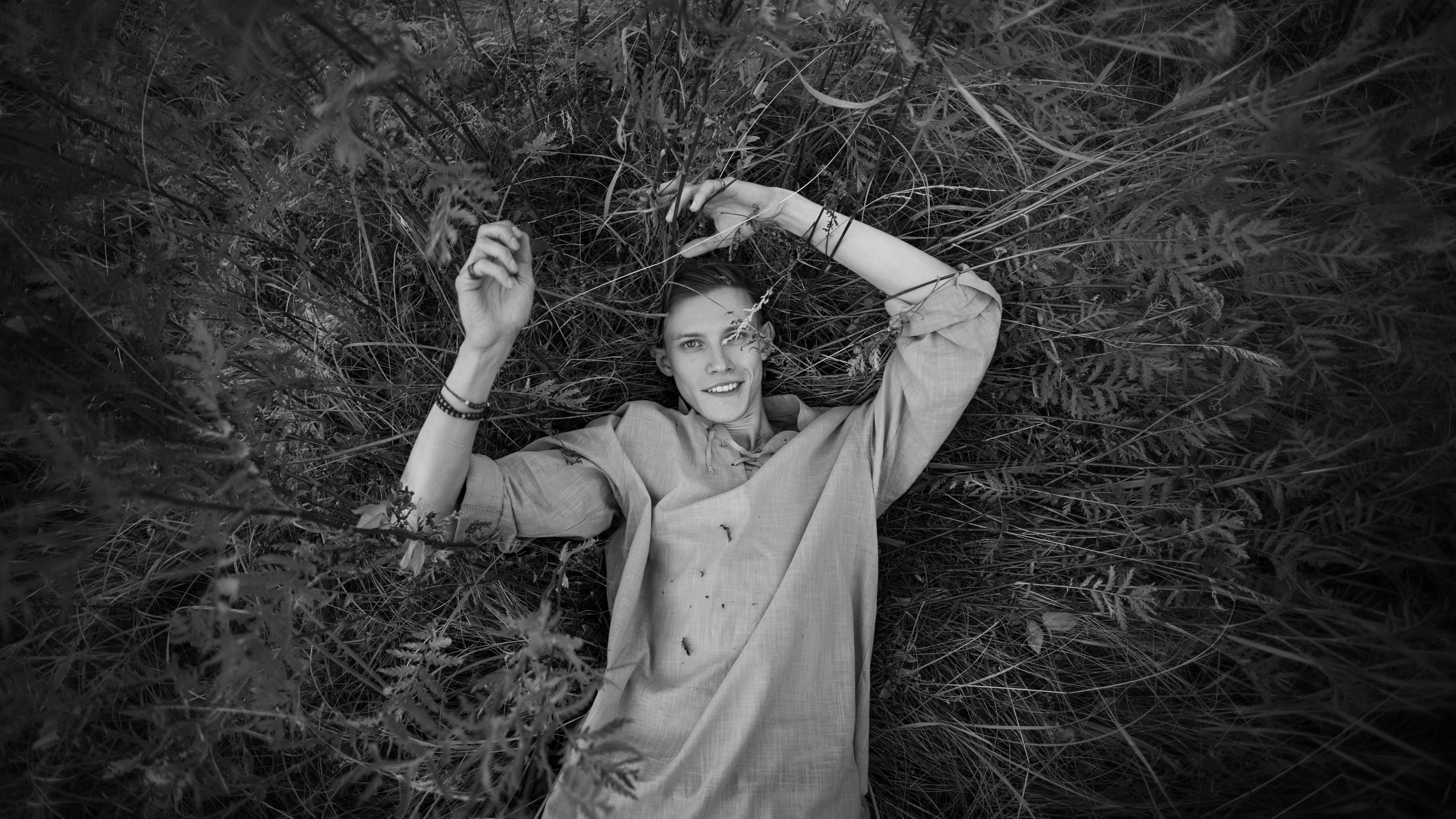 Молодой парень лежит в густой траве на поляне