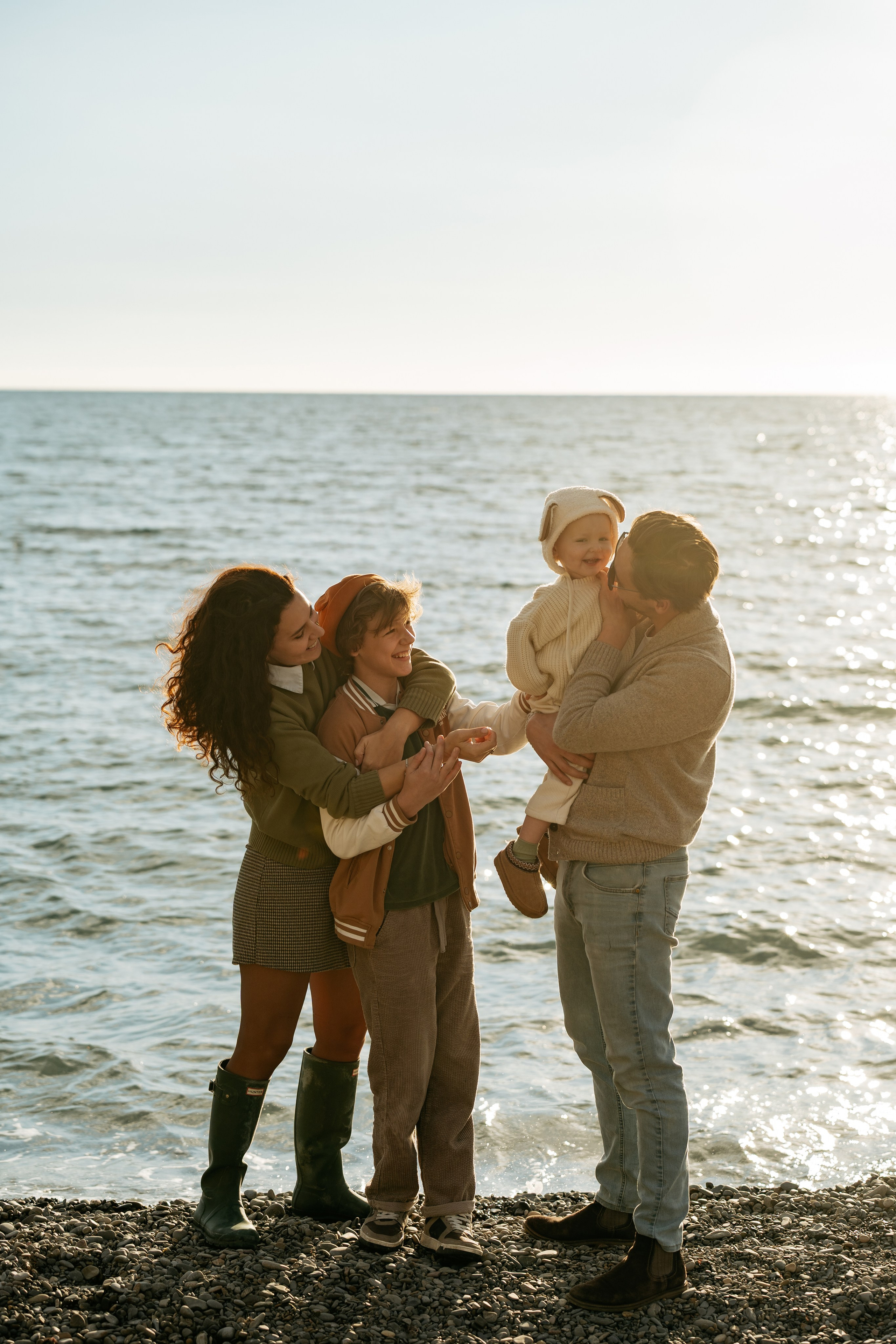 Профессиональная семейная фотосъемка в Новороссийске. Фотограф ловит искренние моменты между братом и сестрой на каменистом пляже.
