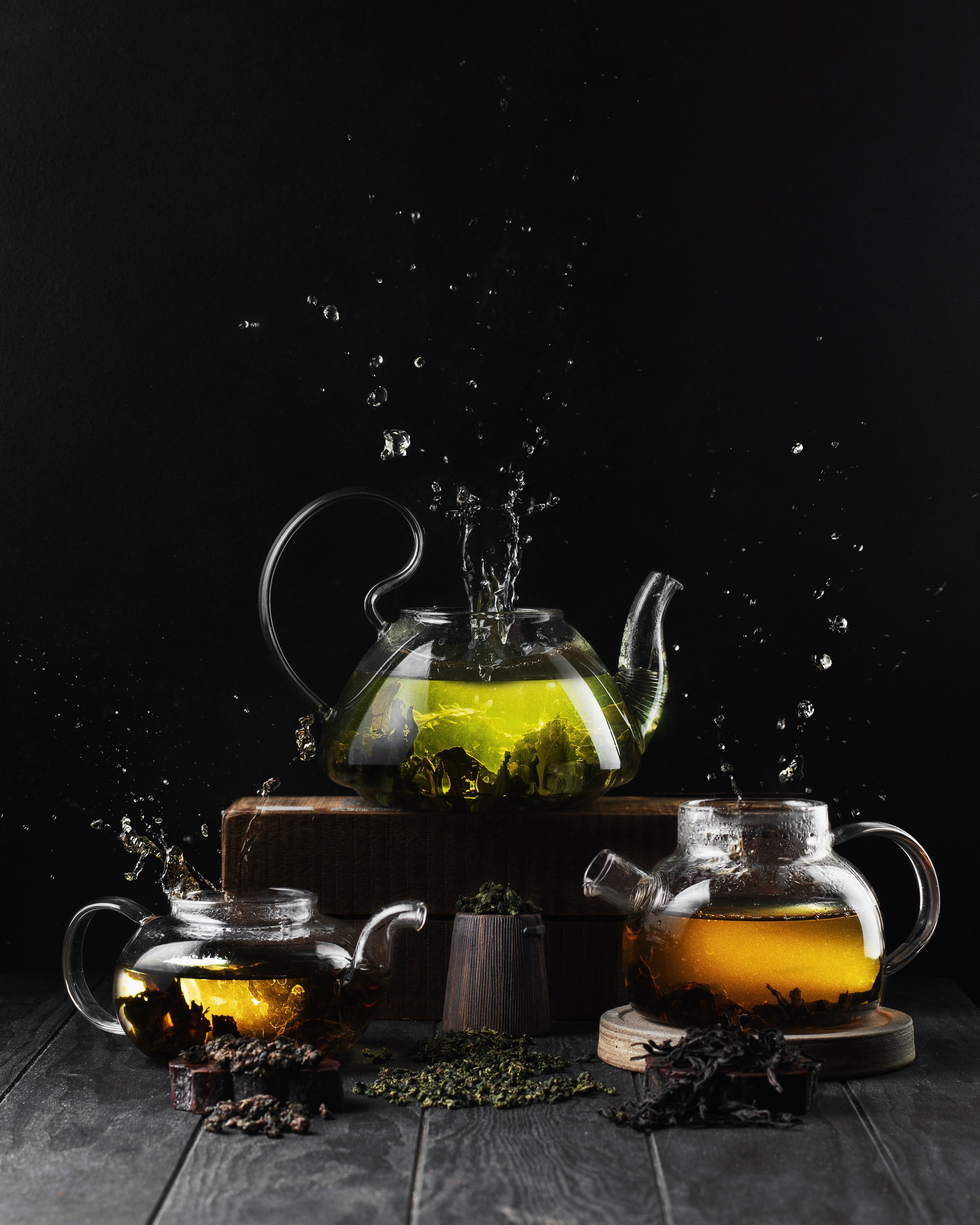 фотография чая на темном фоне, три чайника, с брызгами