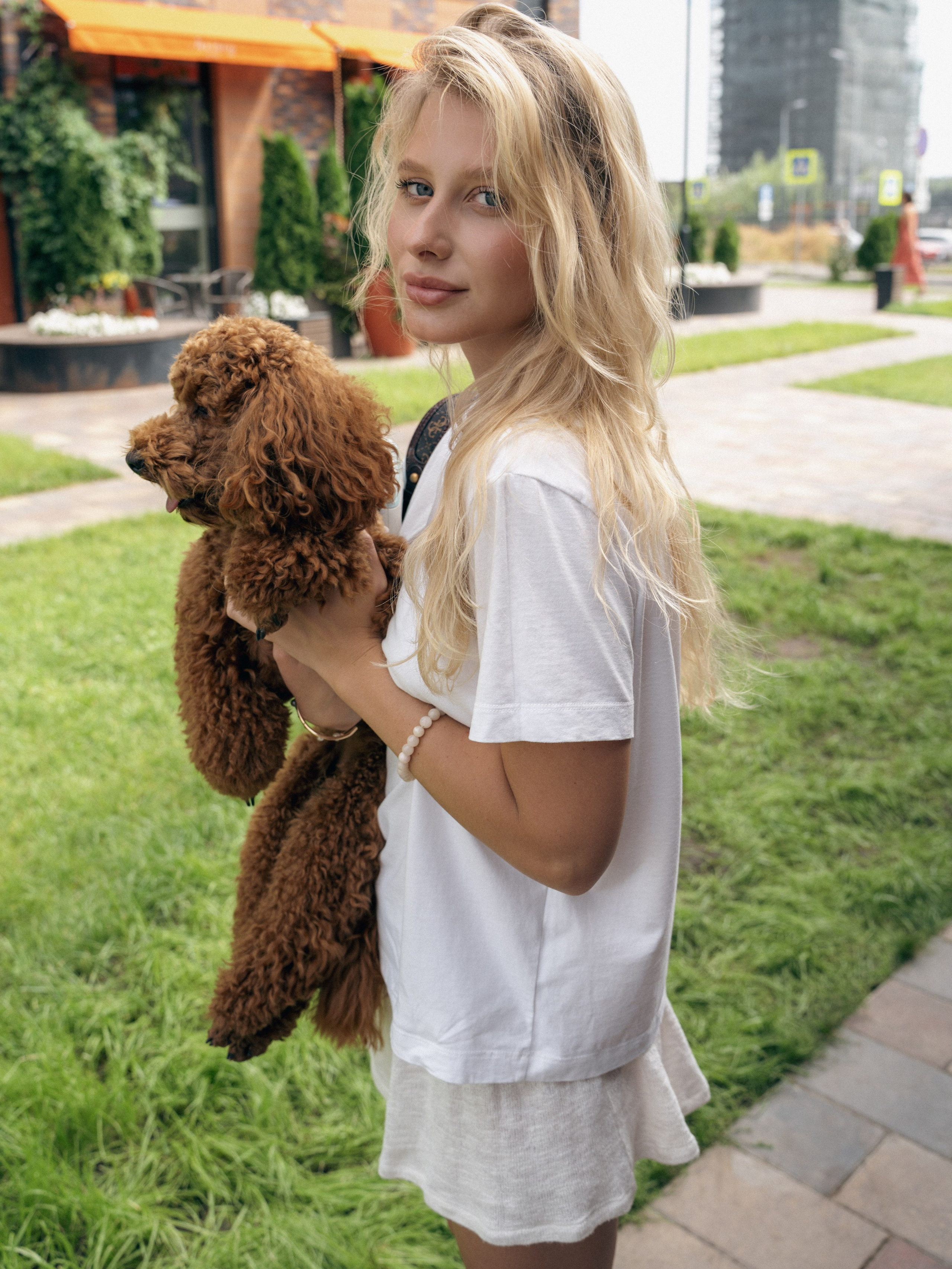 Стильная девушка с маленькой собачкой на городской фотосессии