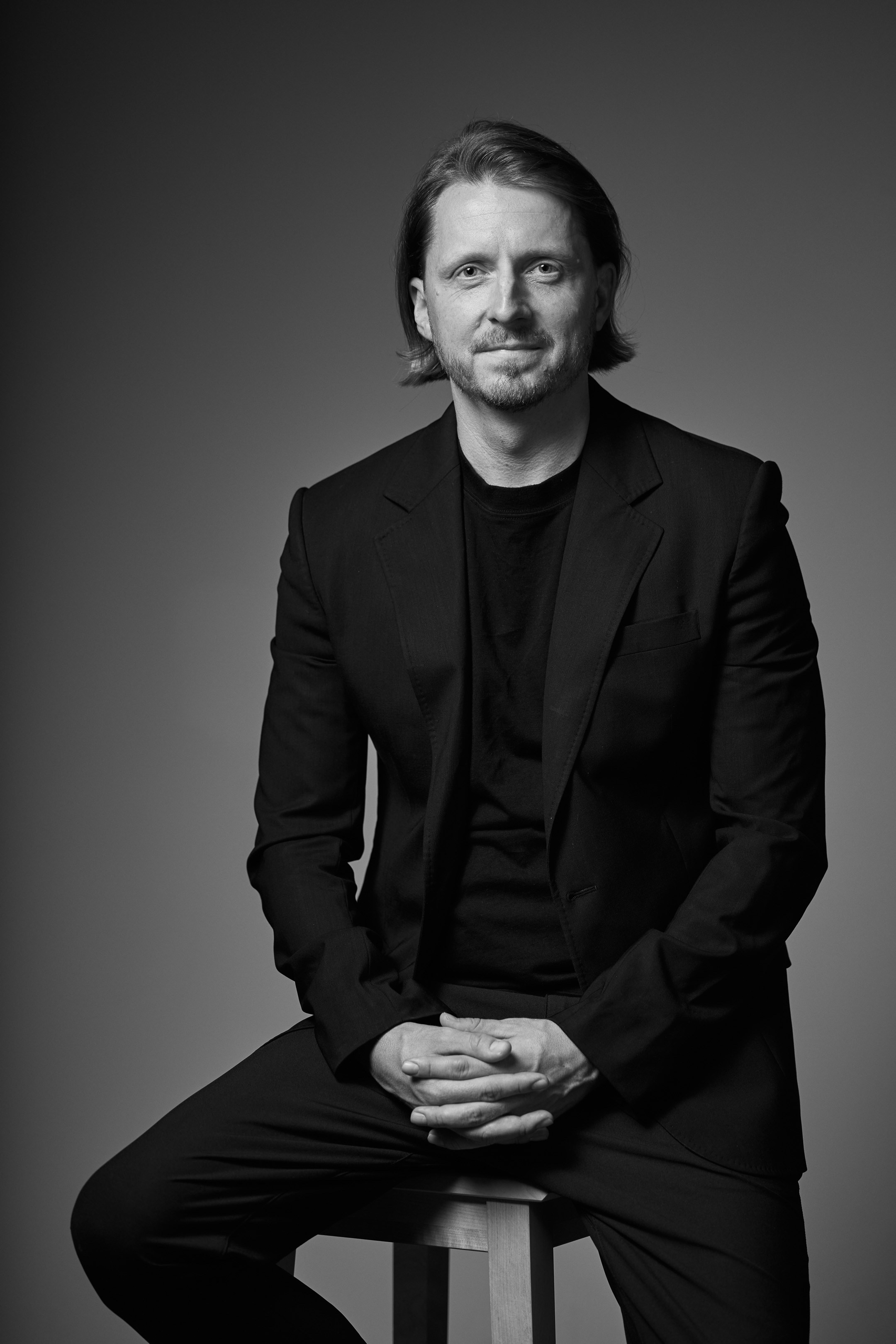 Black and white business portrait of a confident man in a suit on a dark studio background