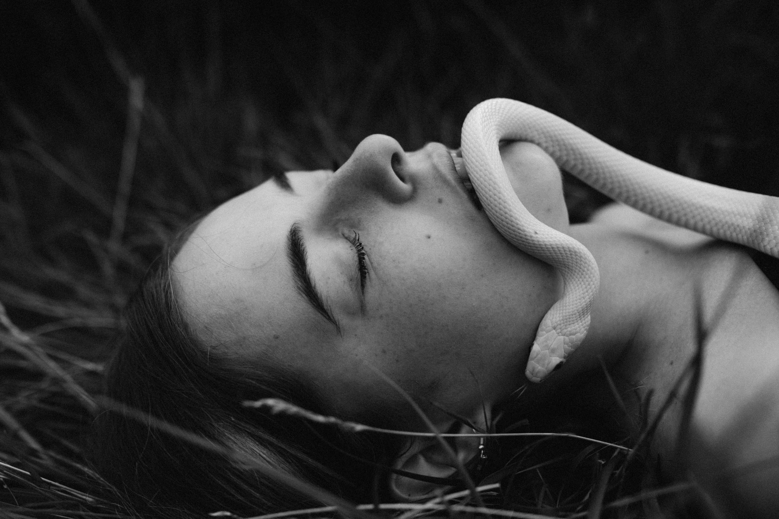 Белая змея ползет по лицу девушки