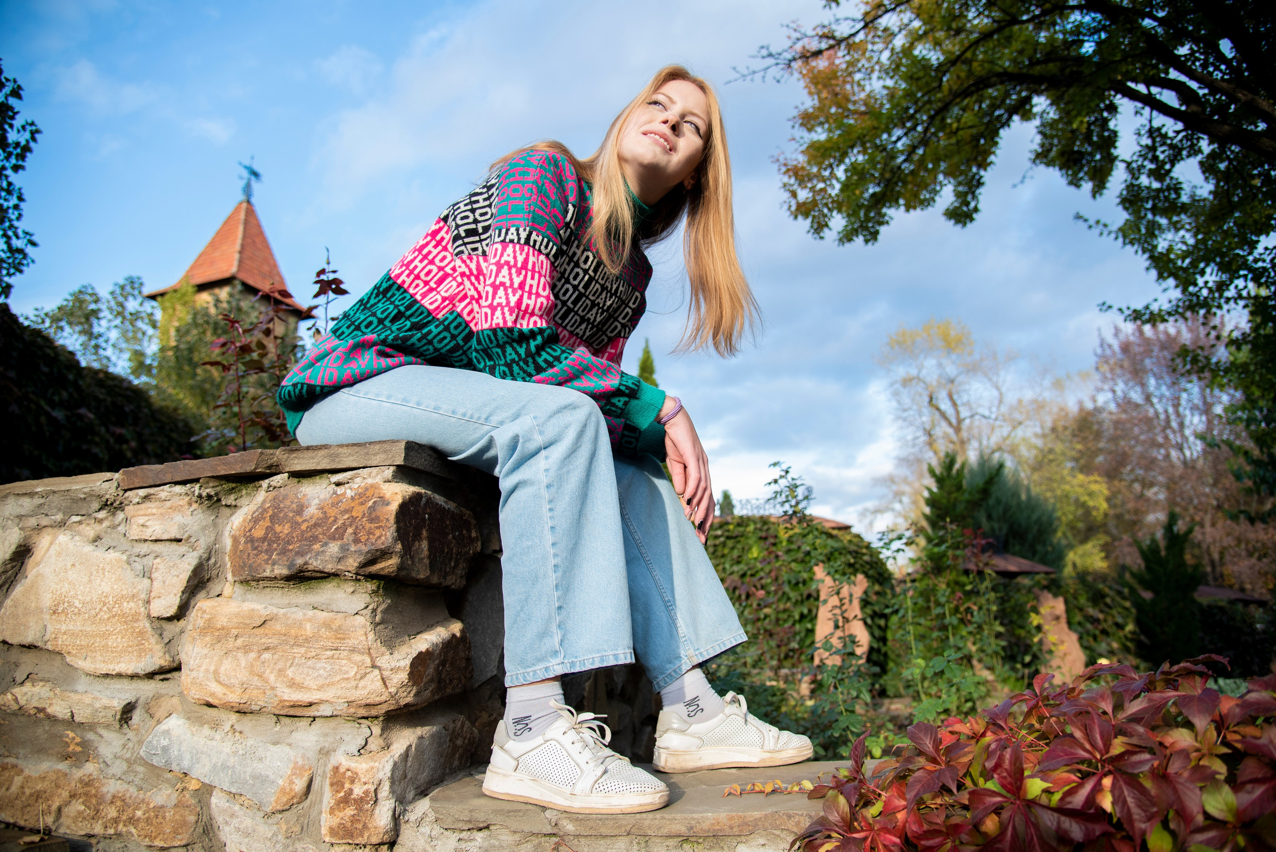 молодая девушка студентка. блондинка. длинные волосы. розово-зелёный свитер. парк Лога . осень широкий угол