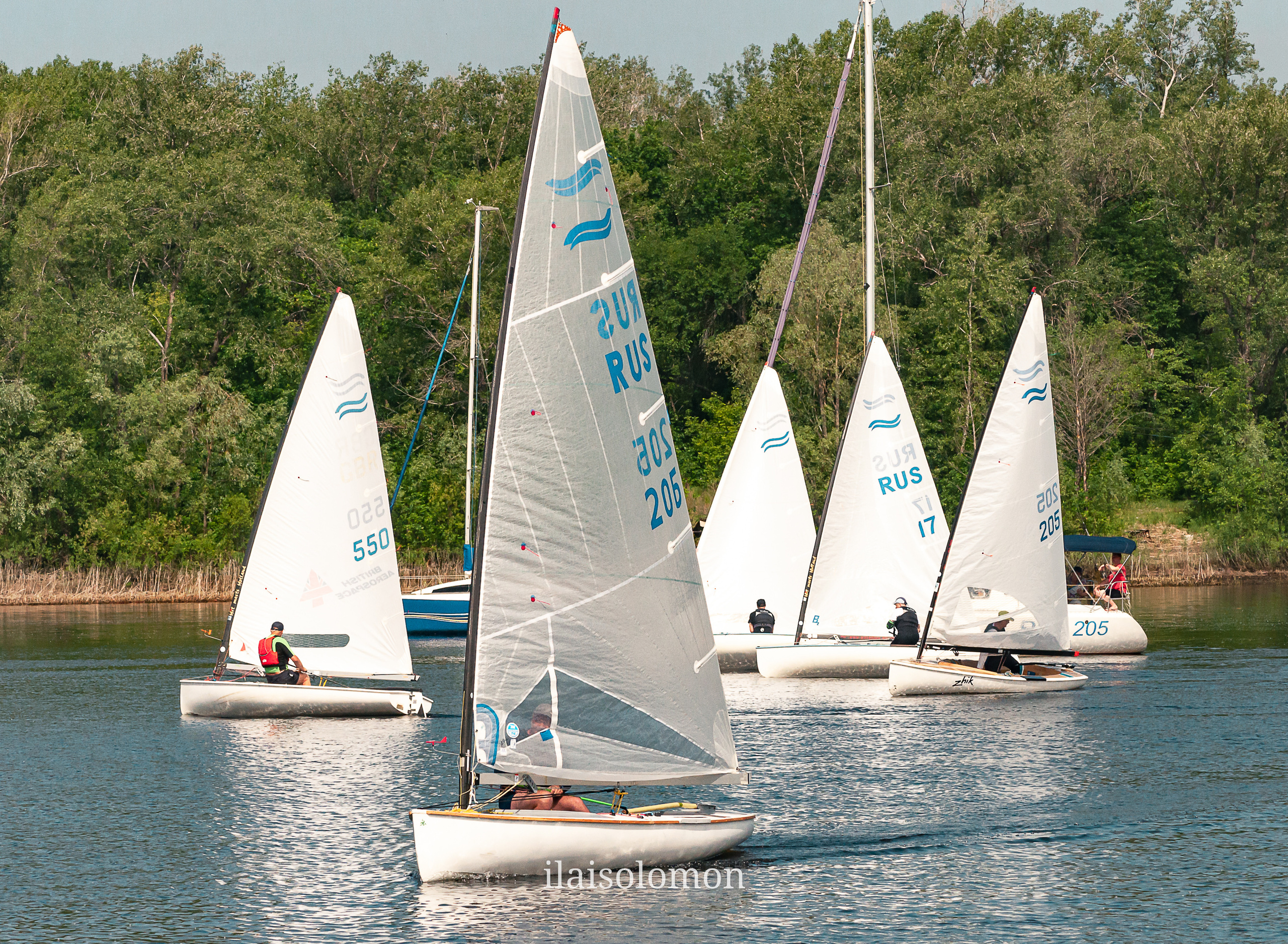 Яхты на старте парусной гонки на Волге, берег с зеленью на заднем плане