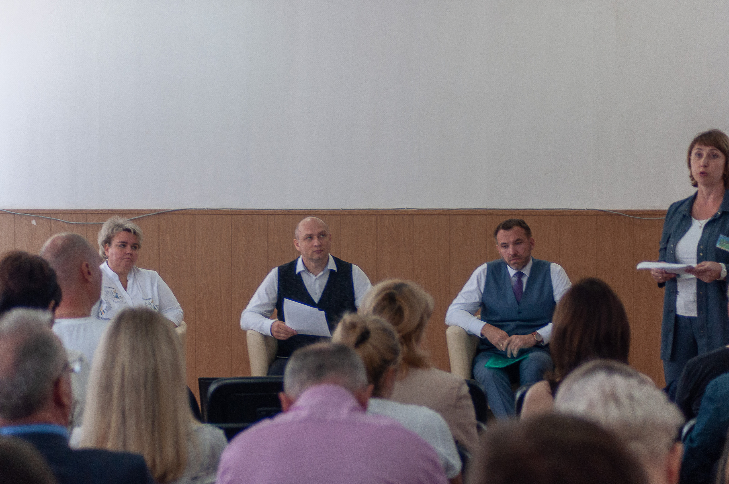 Панельная дискуссия с участием нескольких спикеров перед аудиторией на деловой конференции.