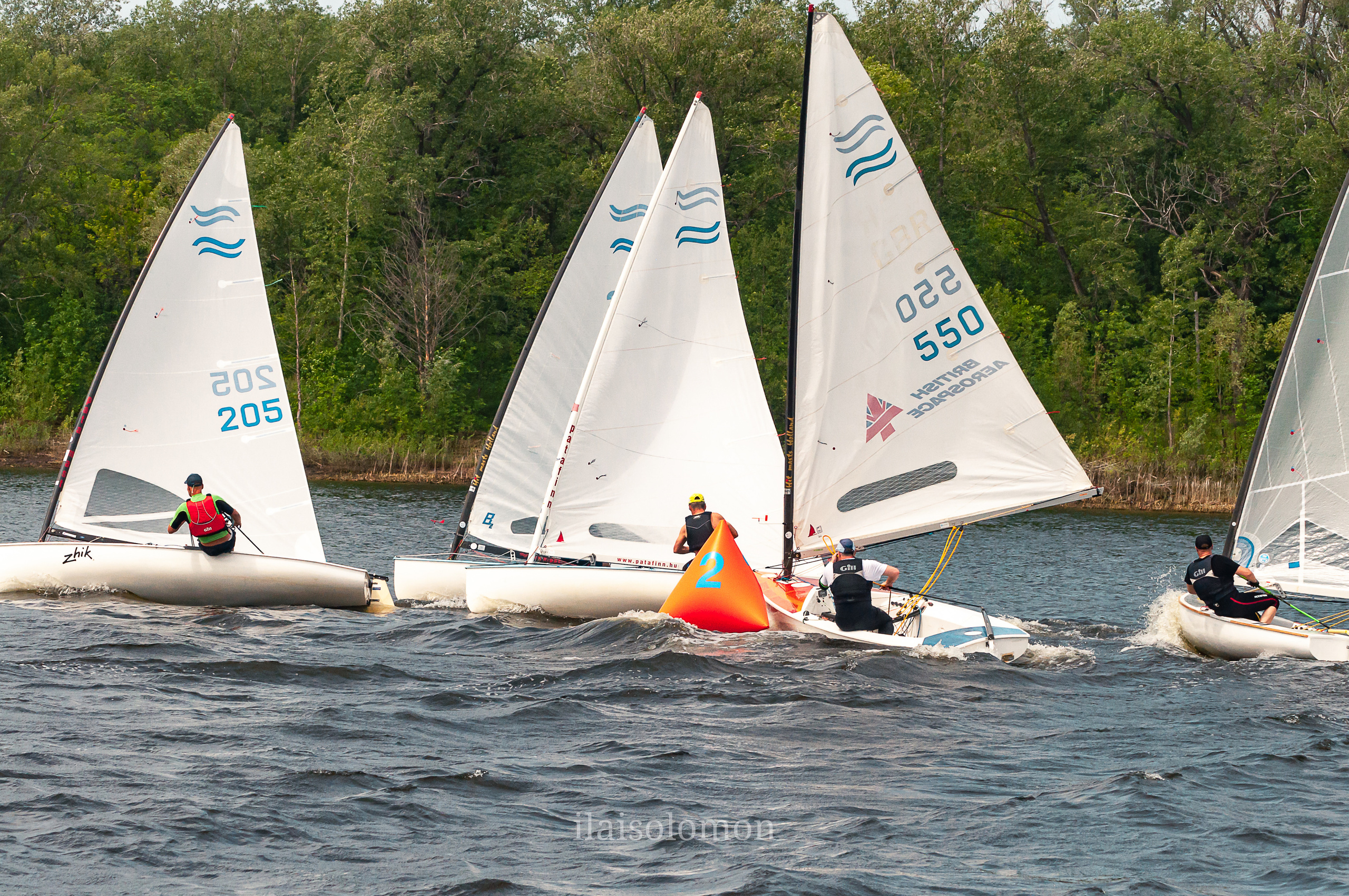 Яхты обгоняют поворотный буй во время напряжённого этапа регаты.