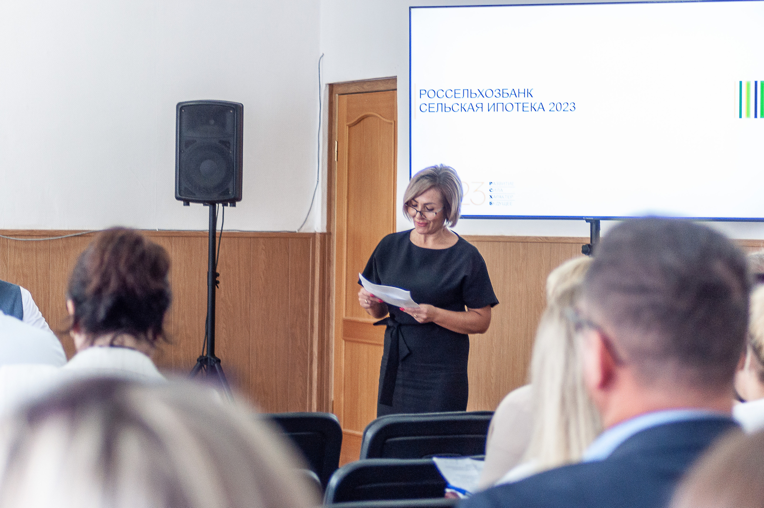 Женщина выступает перед аудиторией с презентацией «Россельхозбанк. Сельская ипотека.