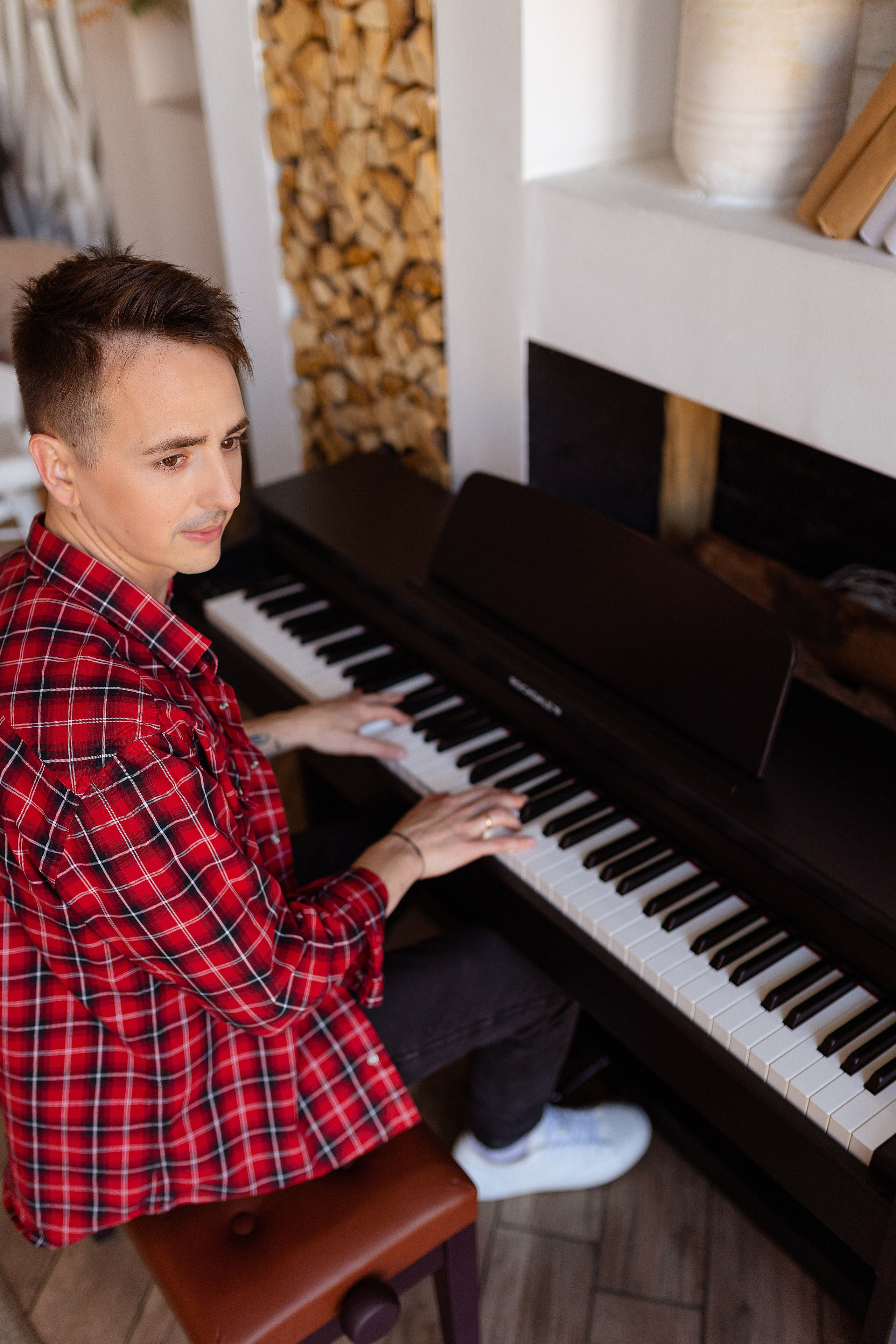 За черным пианино сидит музыкант и играет.