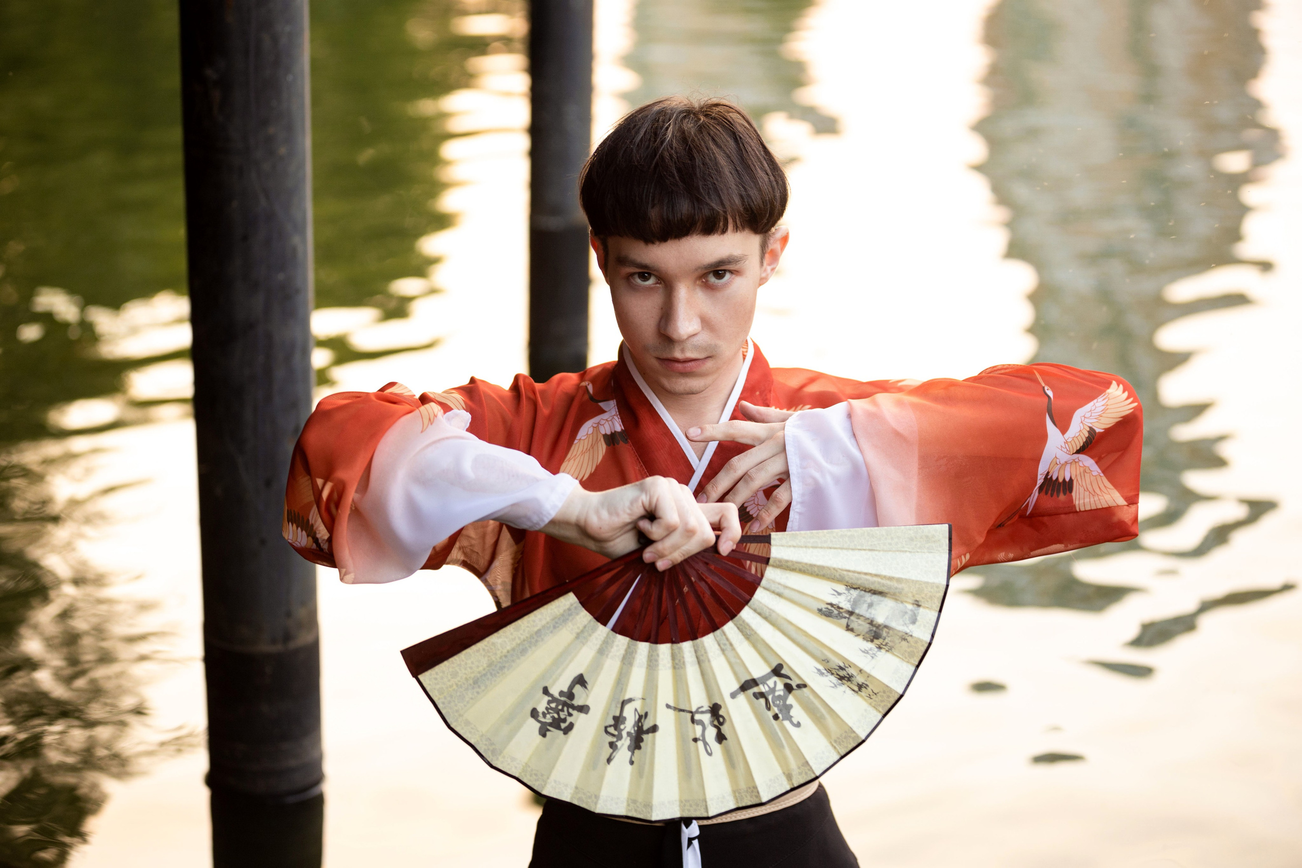 Мужчина на фоне воды перед собой раскрыл полностью веер.