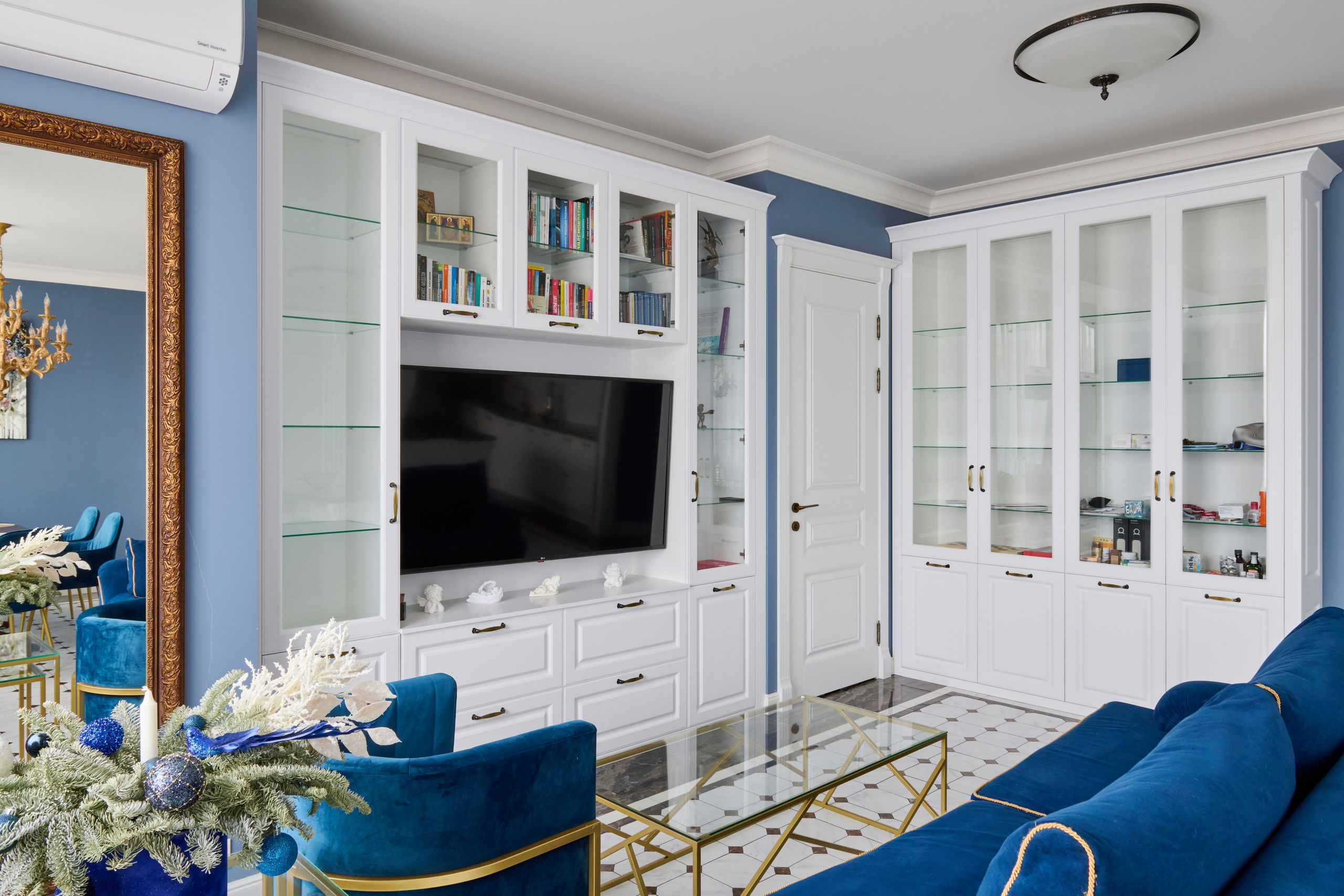 ТВ-зона: встроенные белые шкафы, стекло, синий диван на переднем