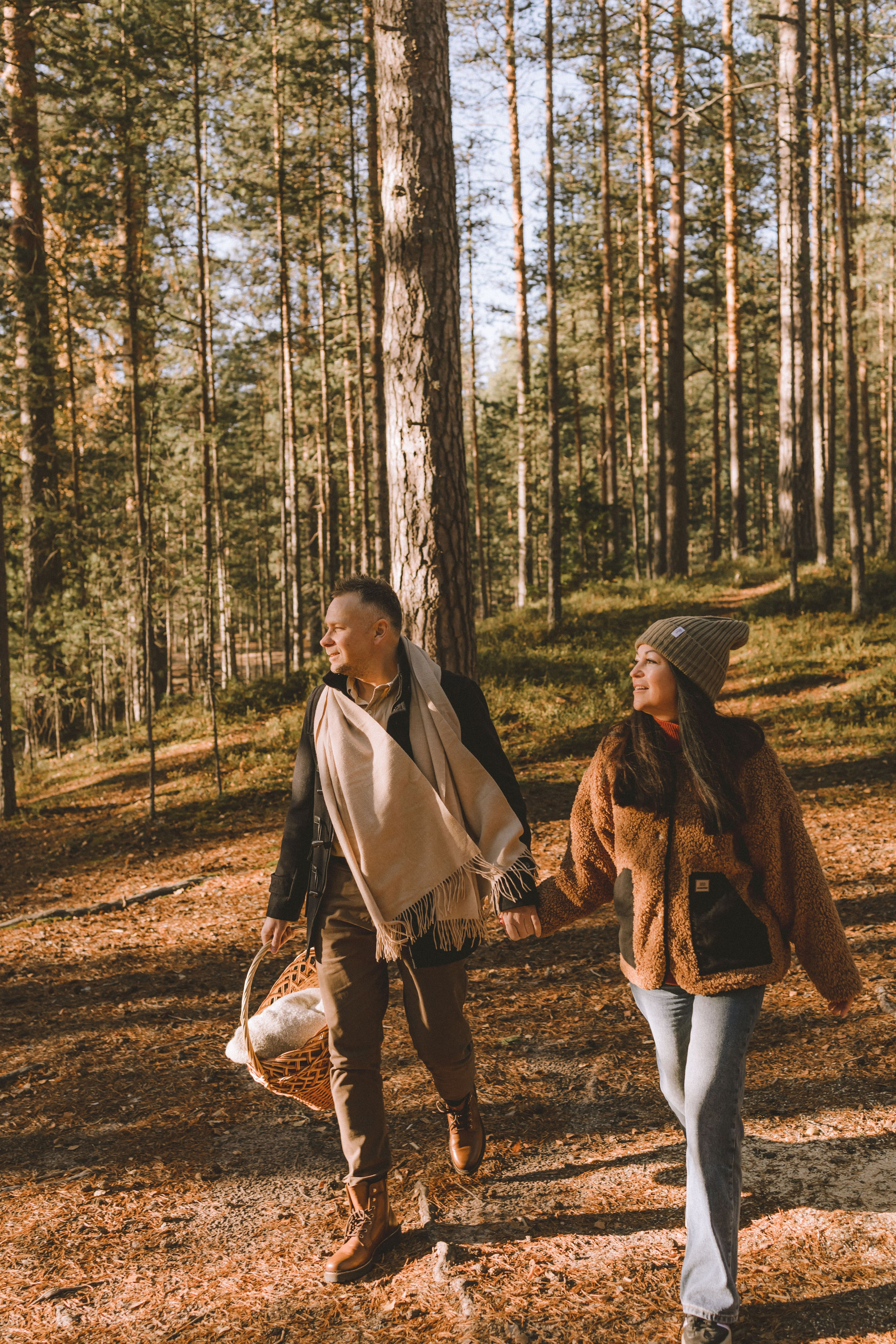 Натуральный осенний пейзаж: молодая семья с сыном идёт рука об руку по лесной тропинке
