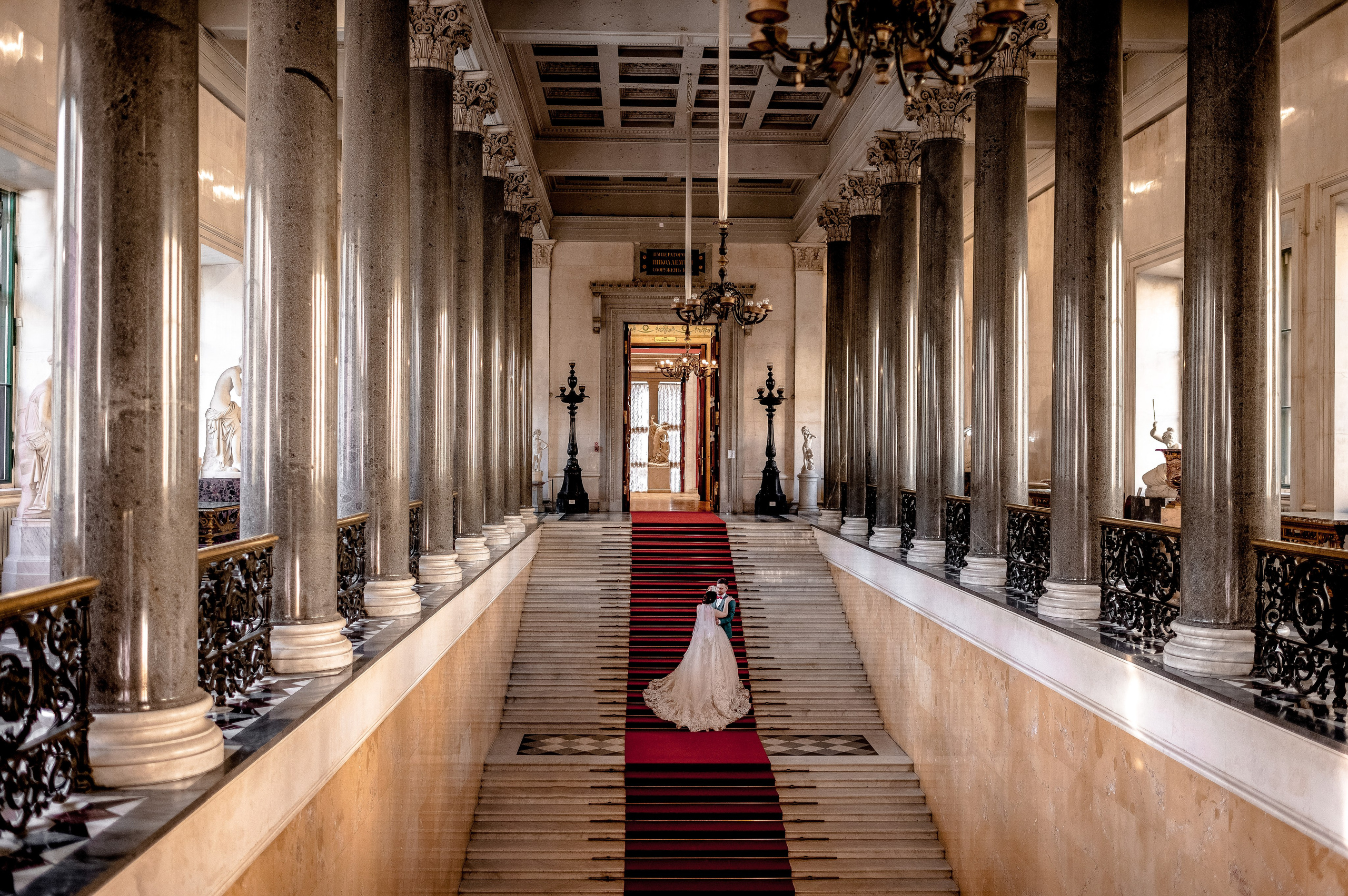 Свадебная пара спускается по эрмитажной лестнице для красивейших свадебных фотографий.