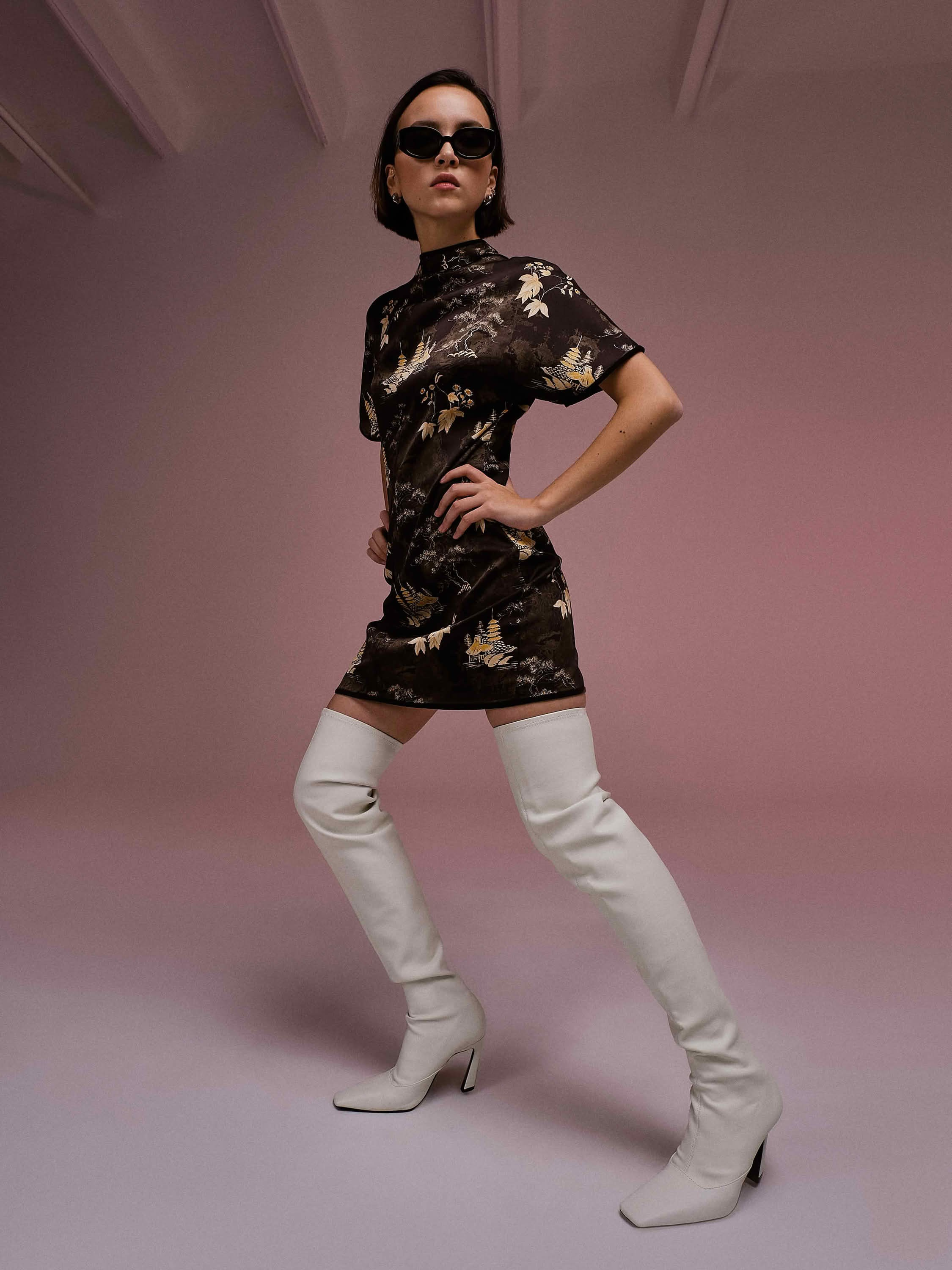 Персональная фотосессия Санкт-Петербург — девушка в мини-платье и белых сапогах позирует на розовом фоне студии