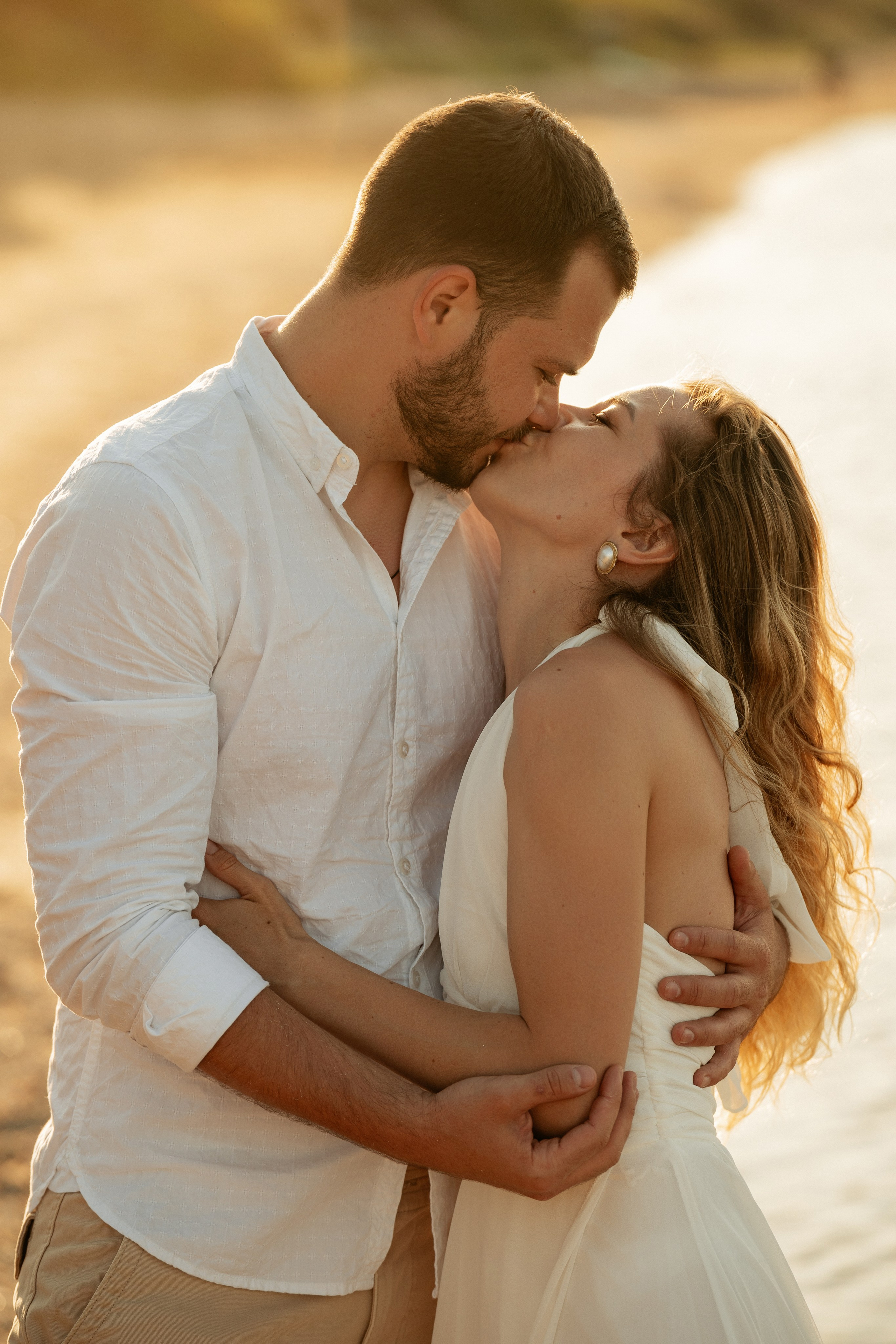 Фотограф ловит момент нежного поцелуя пары среди песчаных дюн в Кучугурах