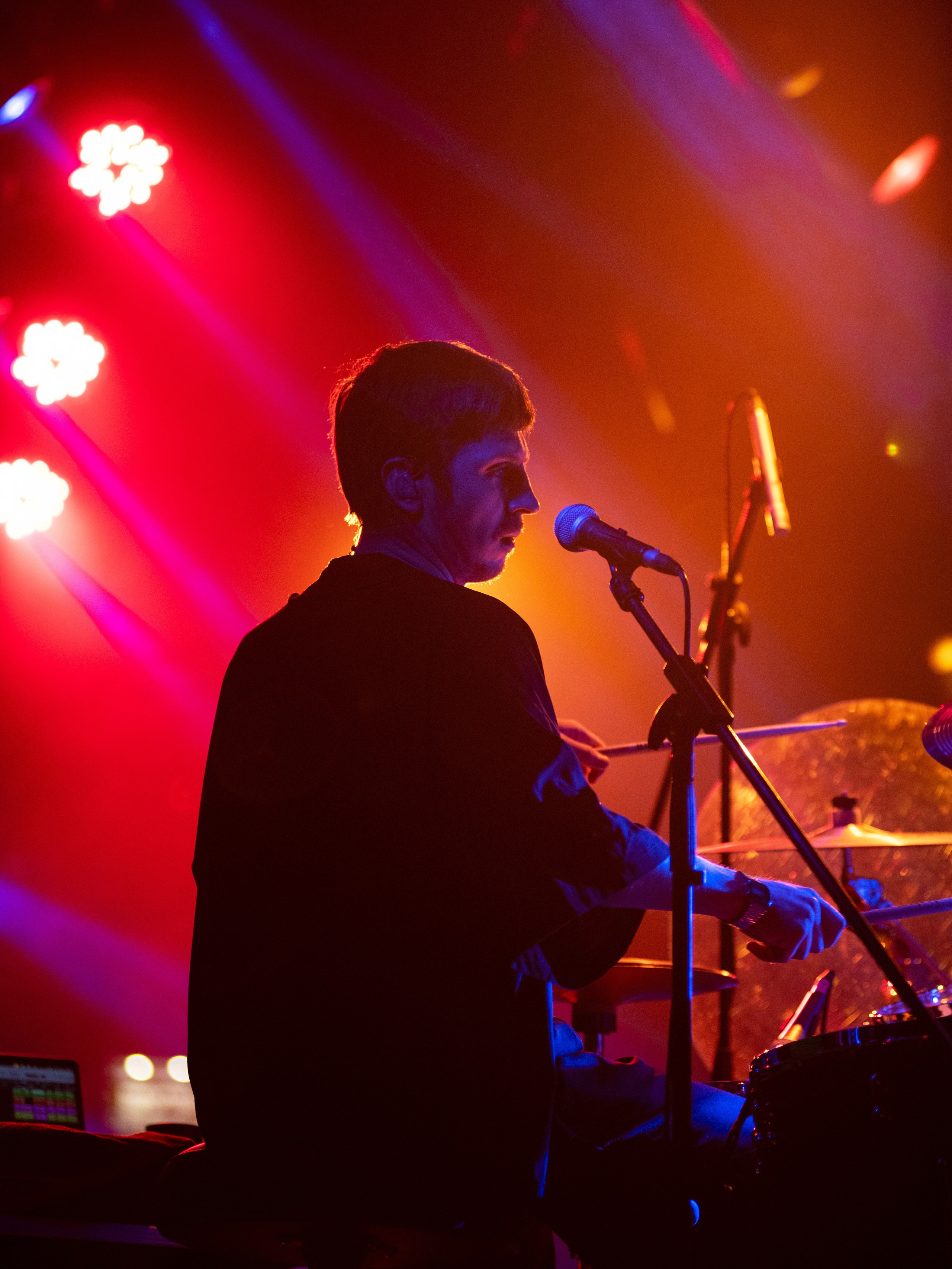 Барабанщик группы «Лампабикт» за установкой в красно-оранжевом сценическом свете