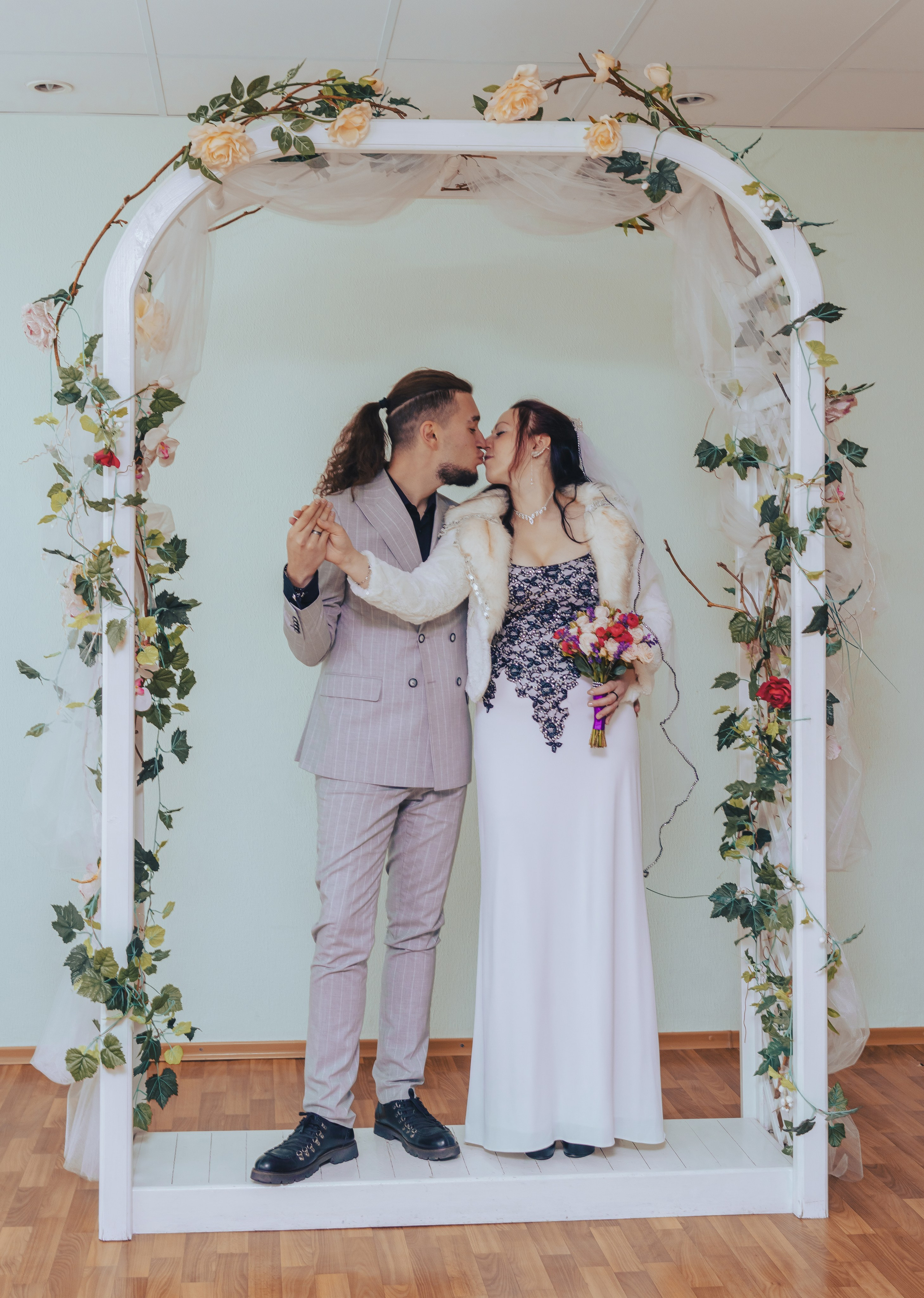 молодые целуются в арке новобрачных