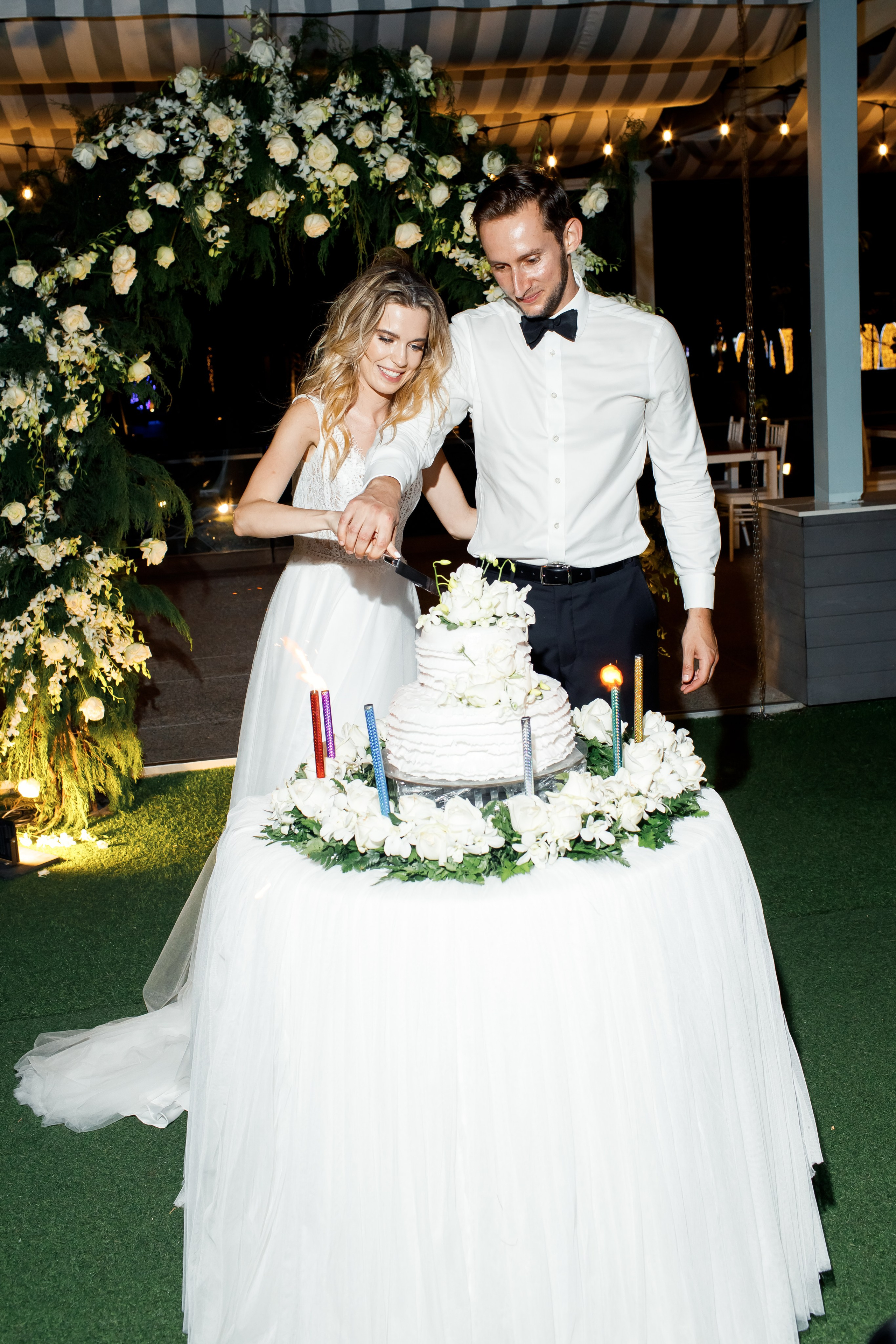 молодожены разрезают торт в окружении гостей