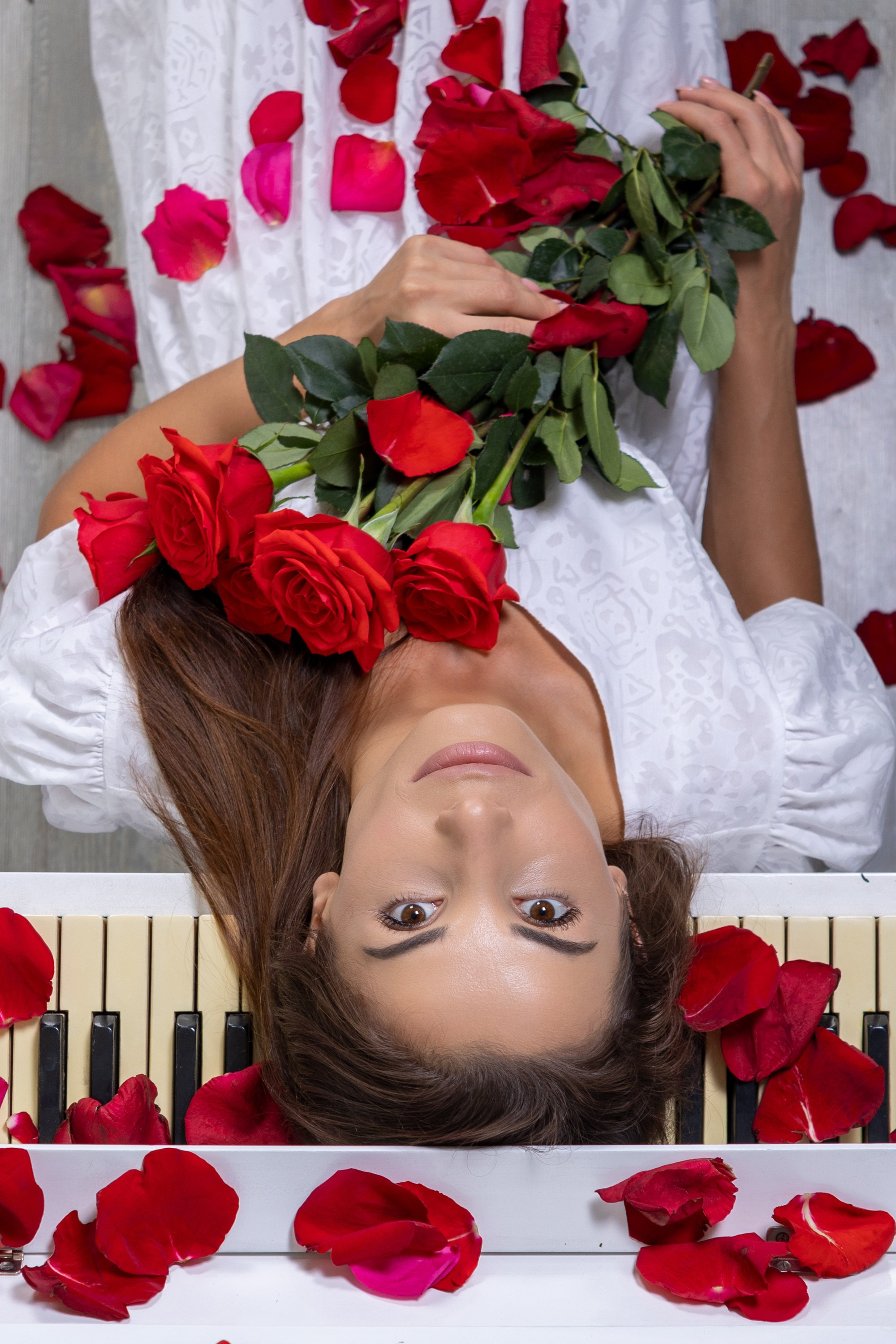 Женский портрет с цветами лепестками роз на пианино красные розы белый фон девушка в белом платье