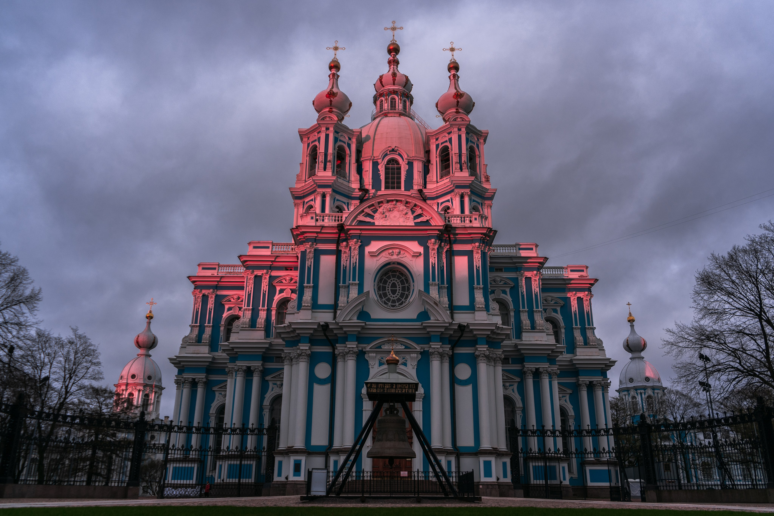 Смольный собор в Санкт-Петербурге вечером, голубой фасад с розовой подсветкой на фоне облачного неба, архитектурная фотография города, фотограф Мальцев Евгений.